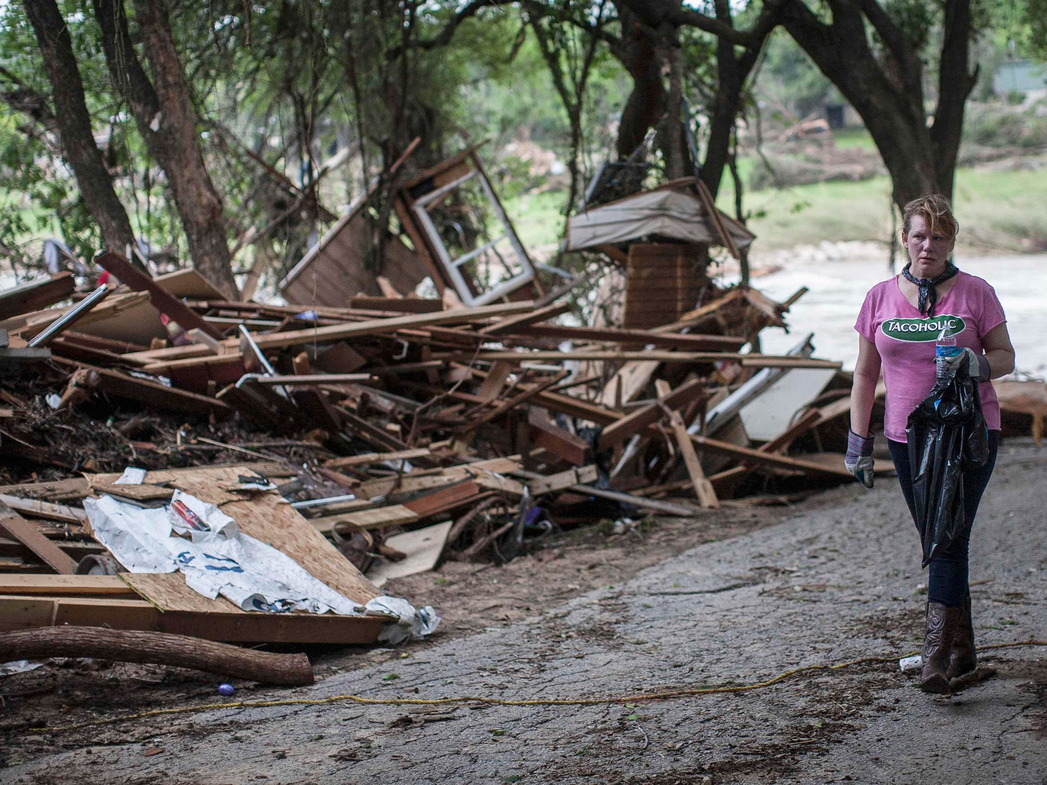 Amy Gilmour, a volunteer from San Antonio, Texas, helps pick up debris from the backyards of flood damaged homes along the Blanco River in Wimberley