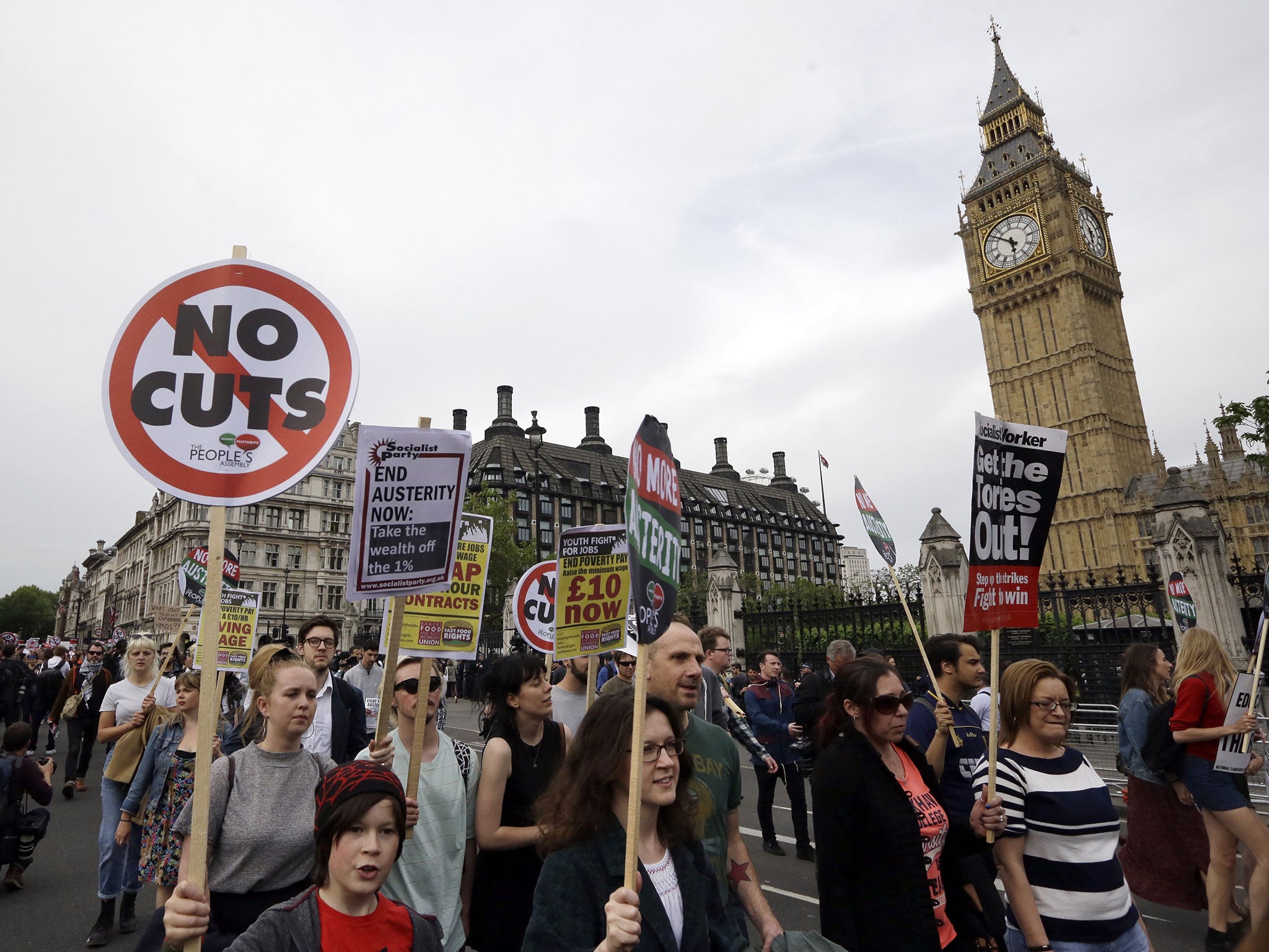 Protesters march with banners during an anti-austerity protest after the Queen's Speech was delivered to Parliament in London, Wednesday, May 27, 2015