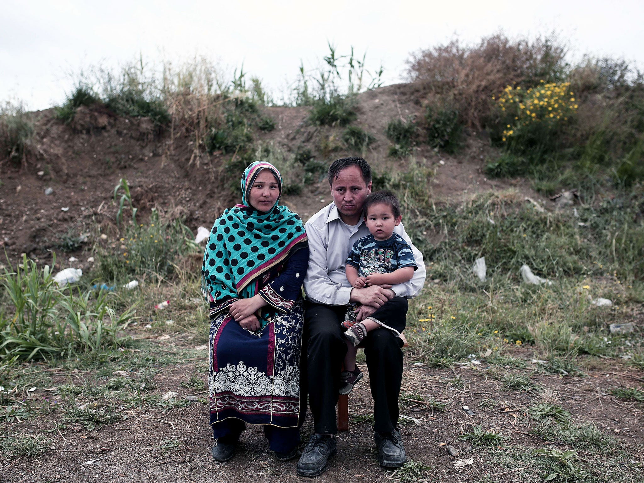 A family of Afghan migrants sit outside of the deserted hotel, where hundreds of migrants have found temporary shelter