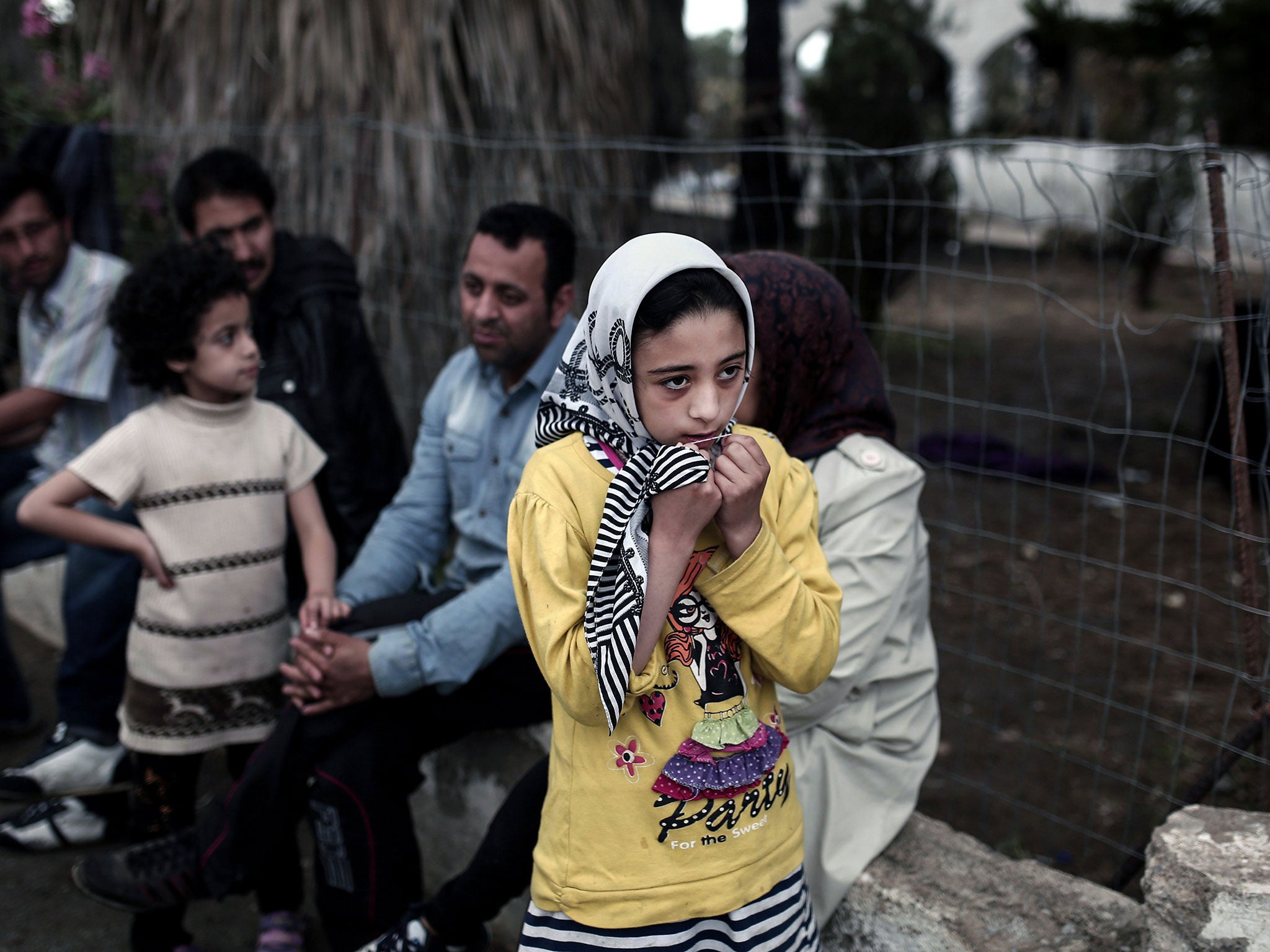 Afghan migrants stand in front of a deserted hotel in Kos