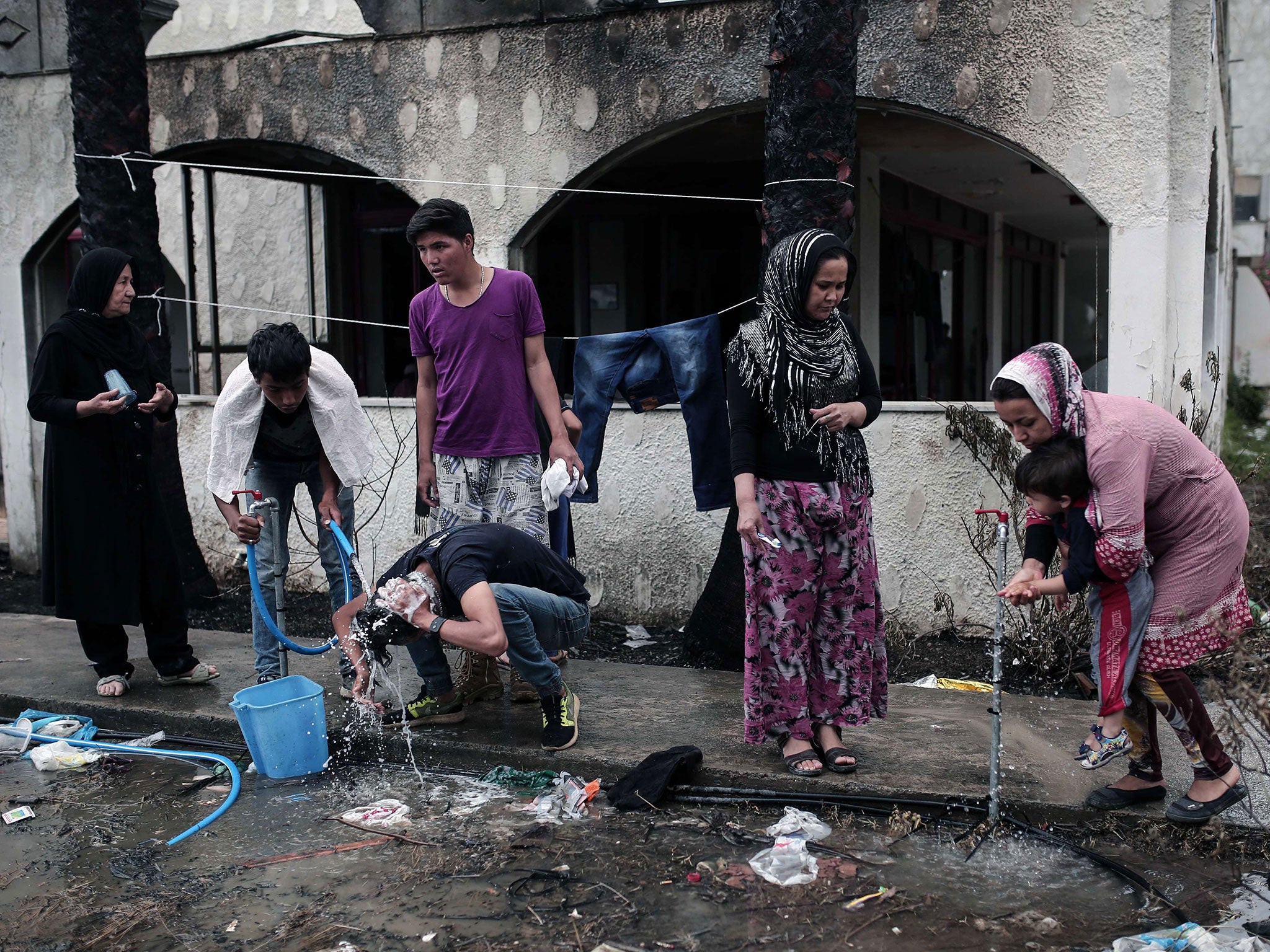 Afghan migrants wash next to a deserted hotel