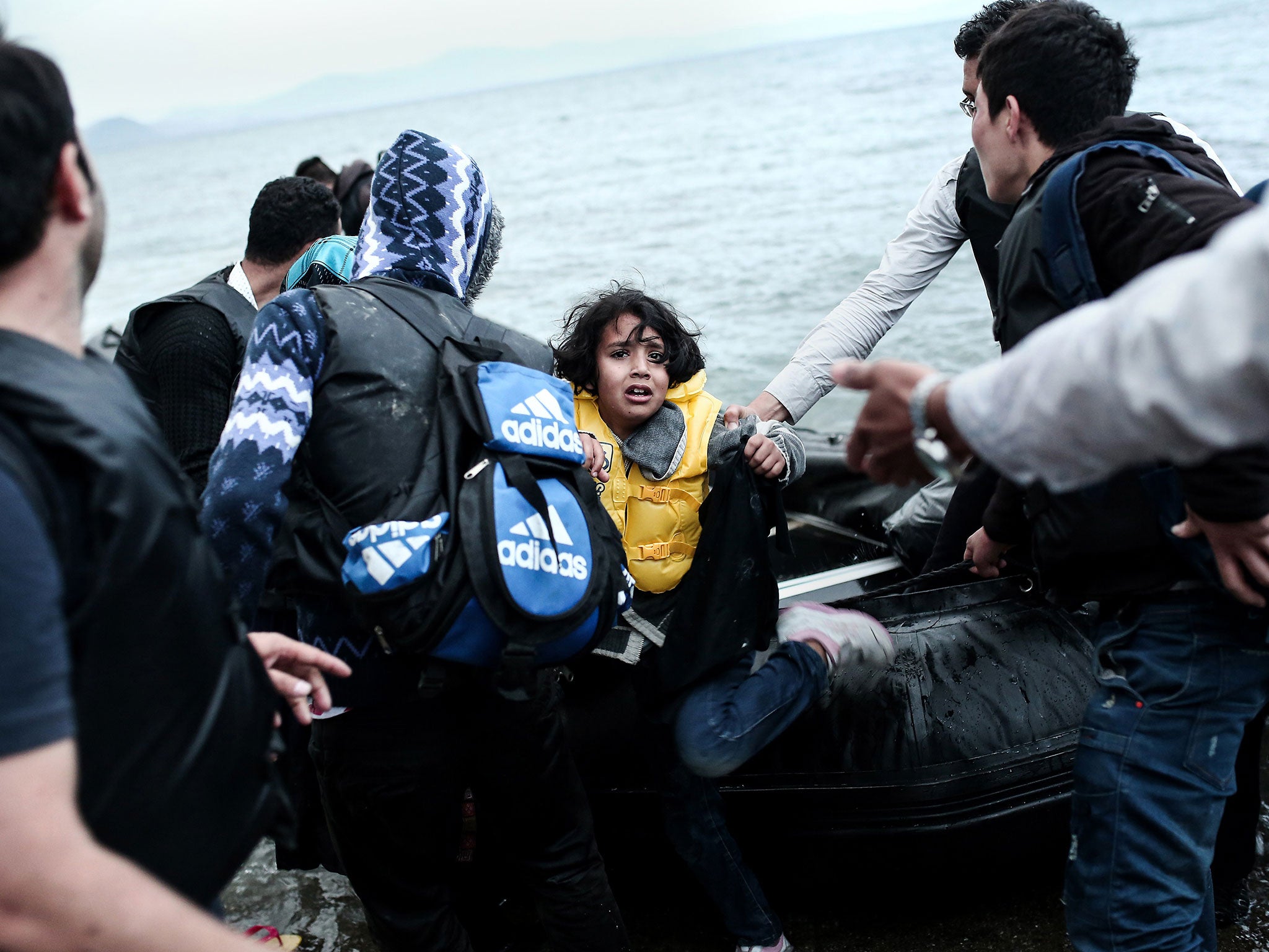 An Afghan child migrant is helped off a rib