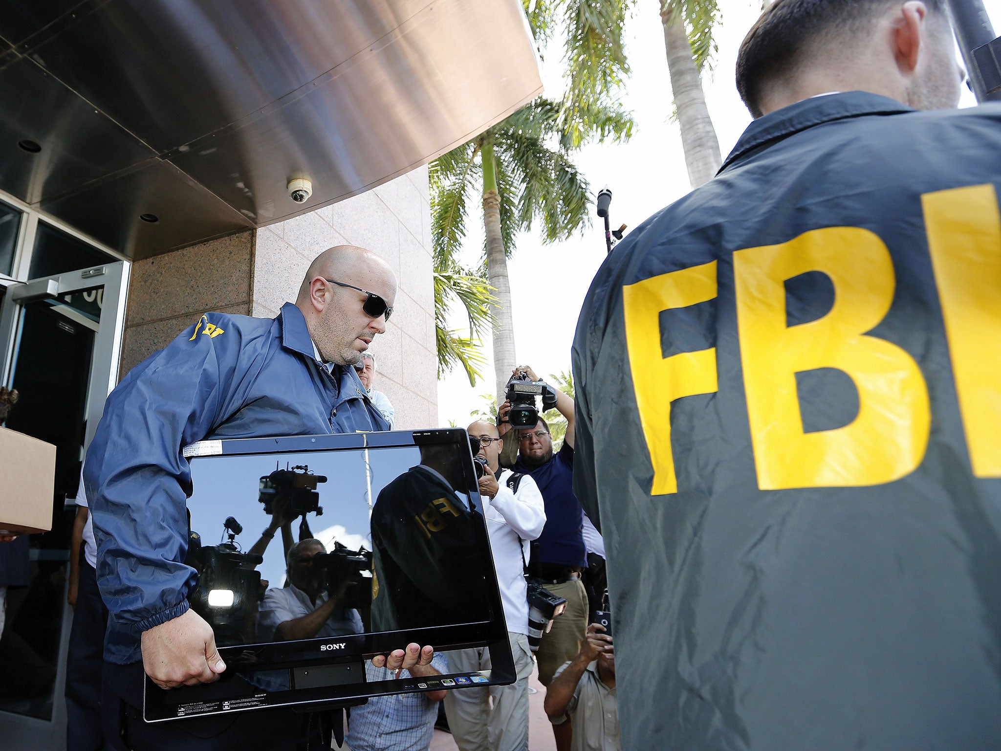 FBI agents carry boxes and computers from the headquarters of the football association Concacaf in Miami Beach, Florida, after a raid