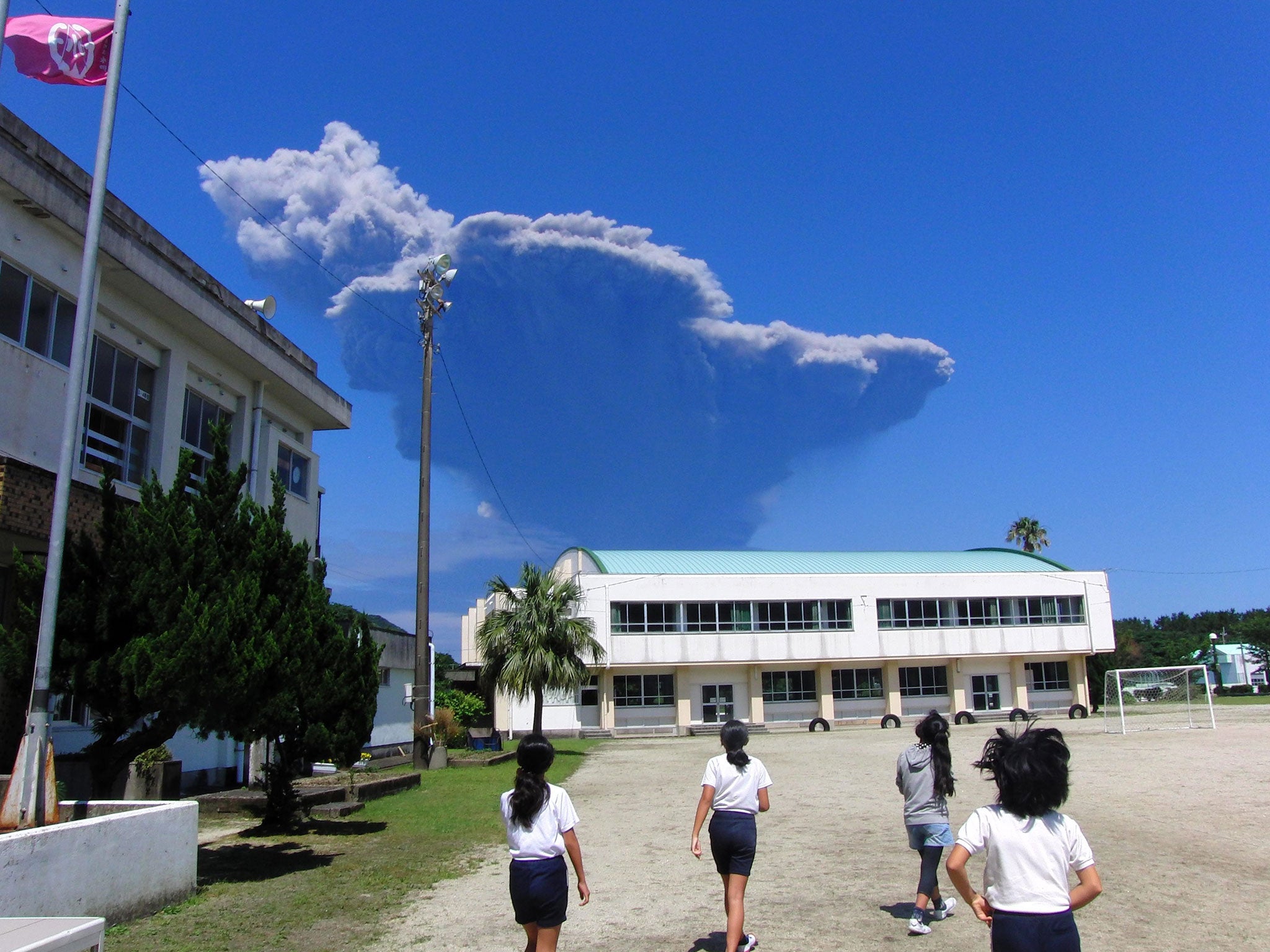 Schoolchildren at Nagata Elementary School on Yakushima Island looking towards volcanic ash rising from Mt. Shindake on Kuchinoerabu Island