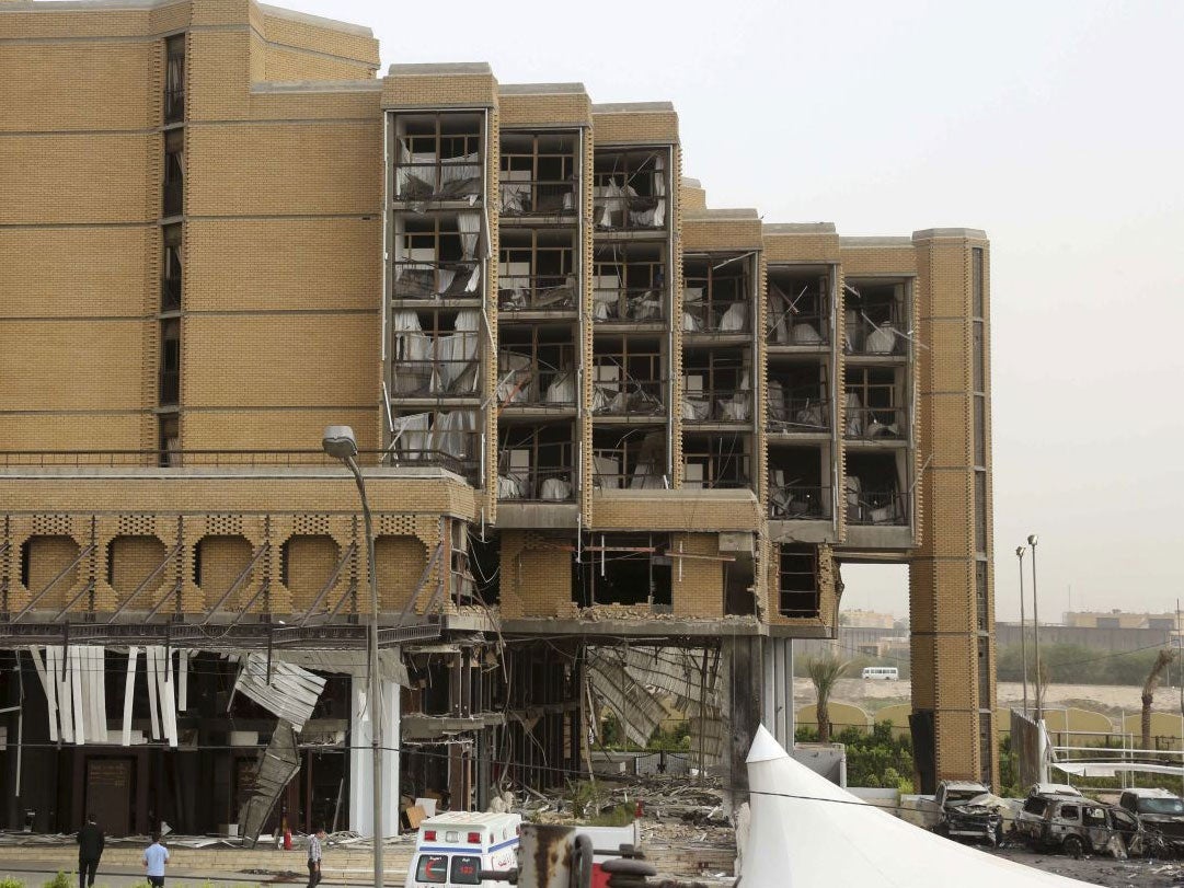 Civilians and security forces inspect the aftermath of a car bomb attack at the Babylon hotel