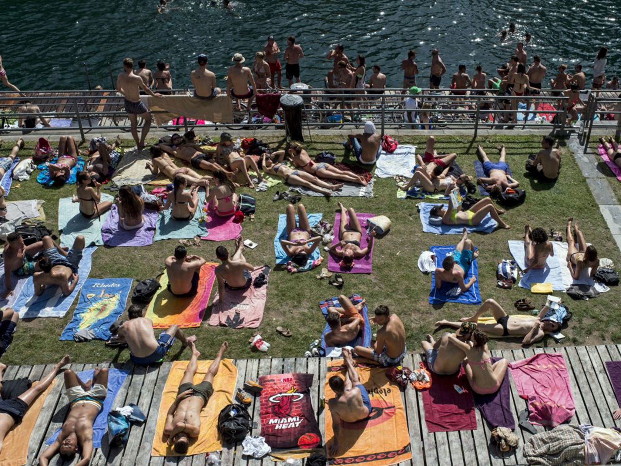 People sunbathe beside the river Limmat