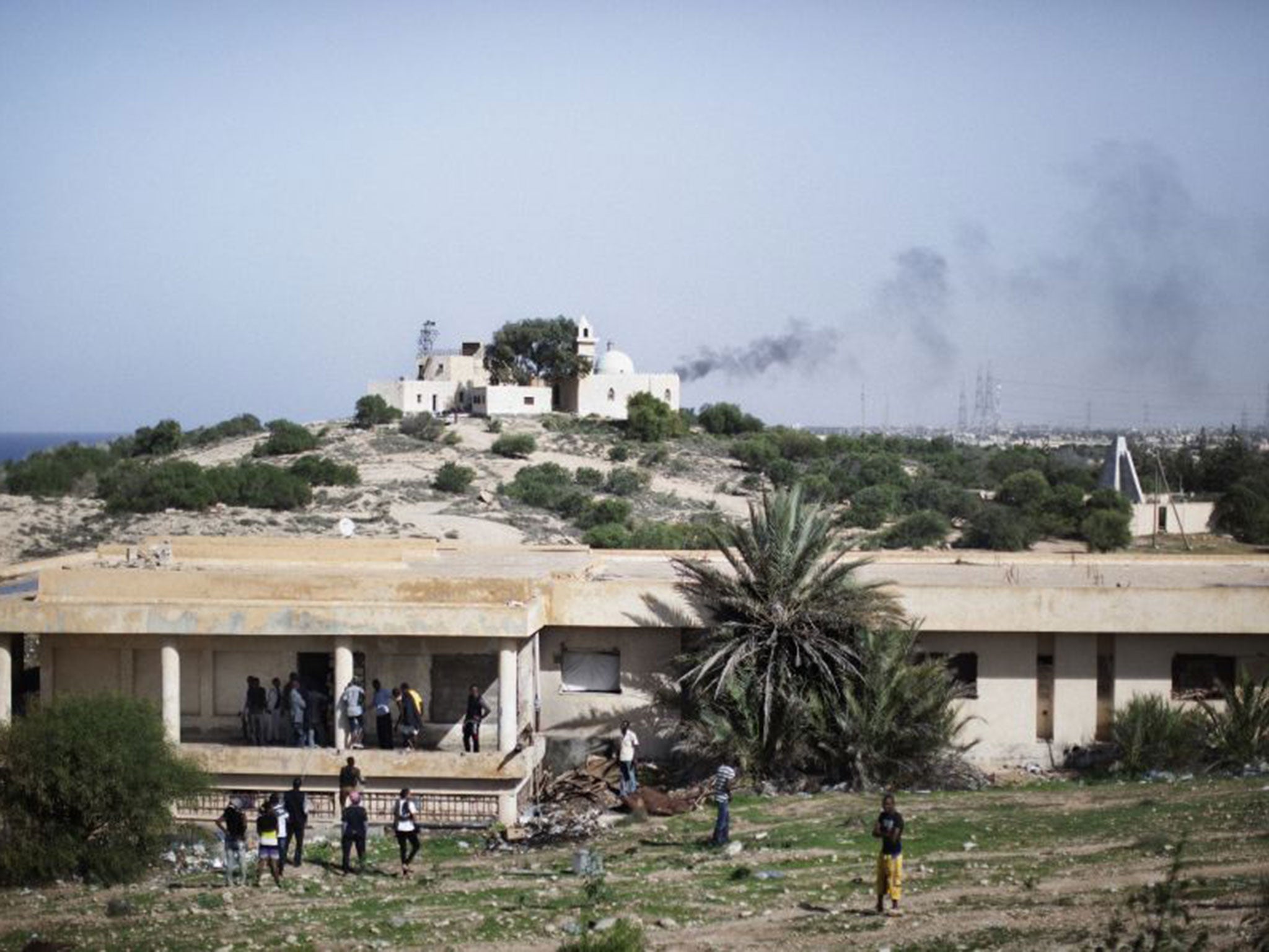 African immigrants gather outside a building used as a shelter at Janzur Port just outside Tripoli