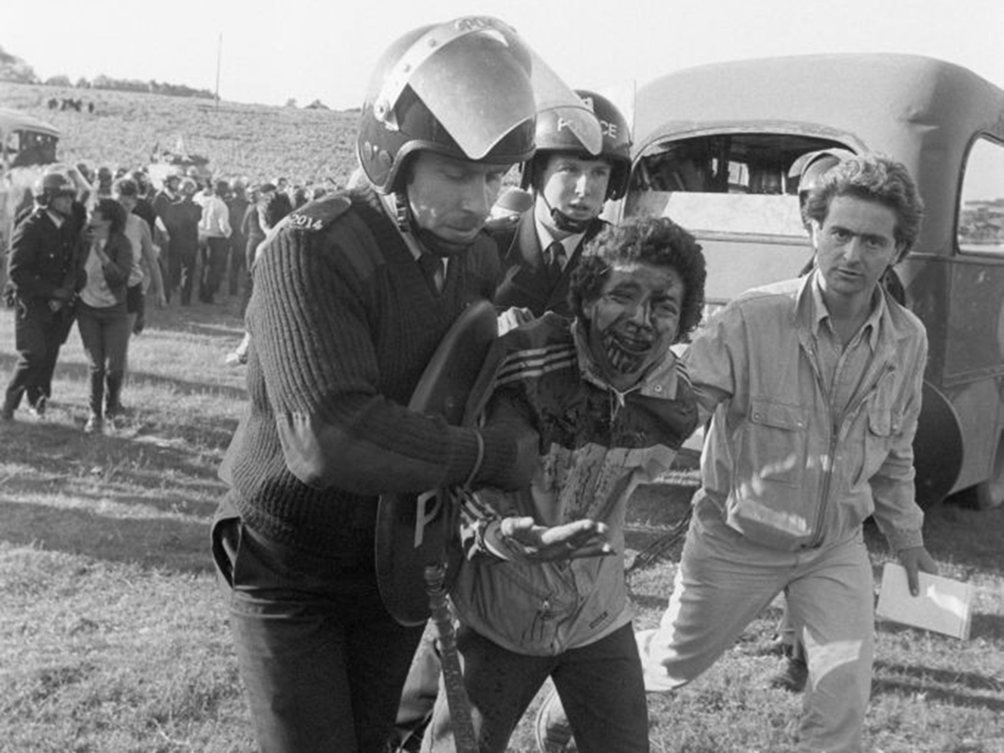 A bloodspattered man from the 'peace convoy' is led away by police.