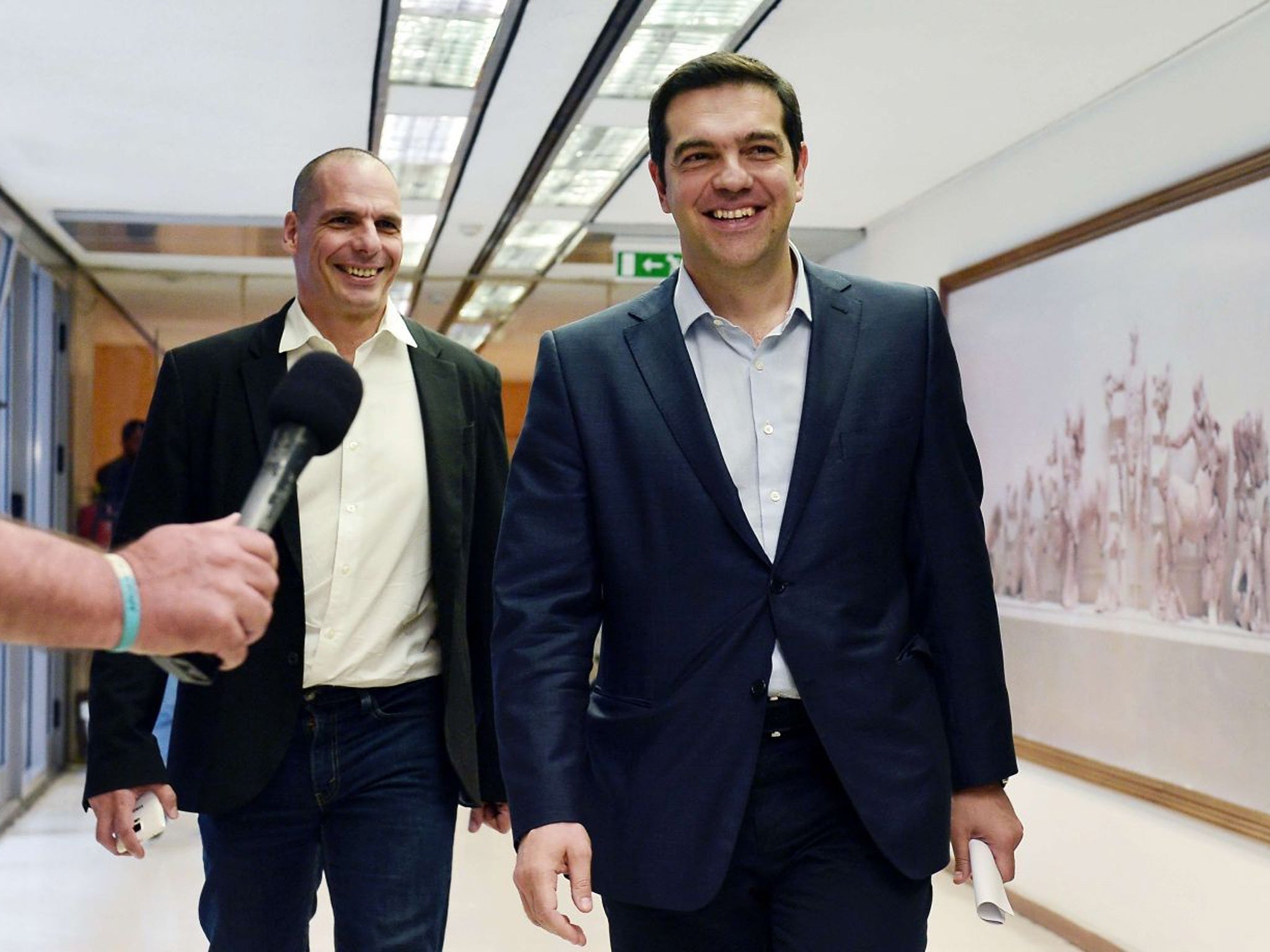 Greek Prime Minister Alexis Tsipras (R) and Greek Finance Minister Yianis Varoufakis (L) smile after their meeting at the finance ministry in Athens in May 2015.