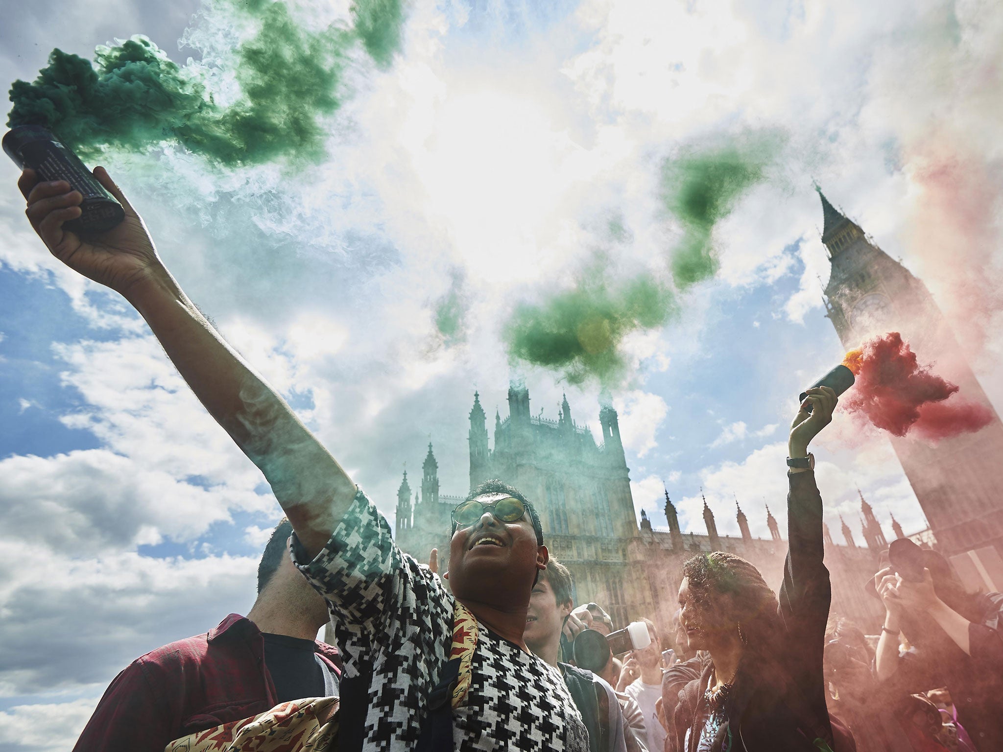 Demonstrators hold smoke canisters as they take part in a protest against the Conservative government's austerity measures in central London