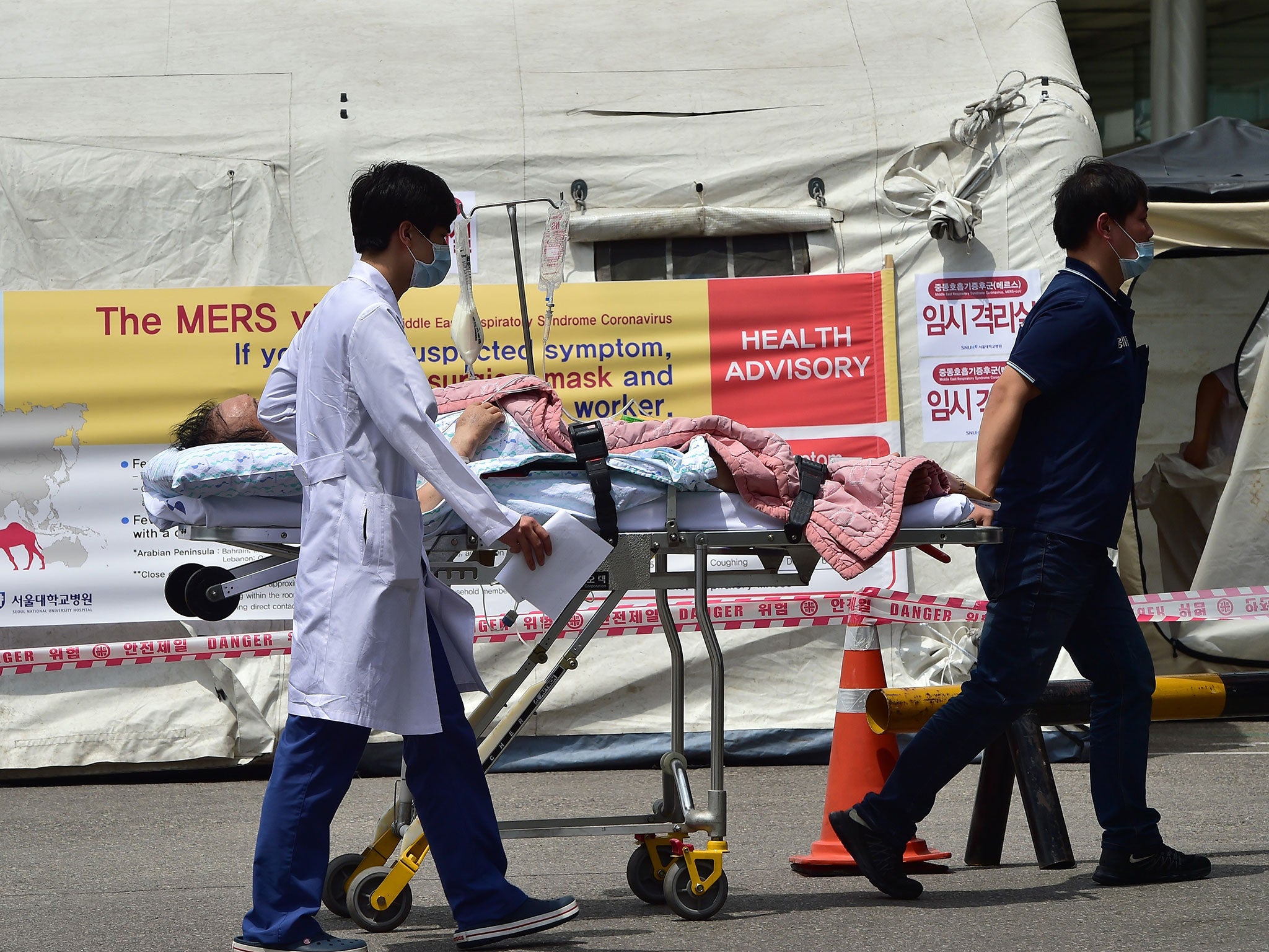 South Korean hospital workers carry transport a man in front of a quarantine tent for suspected MERS cases at the Seoul National University Hospital in Seoul