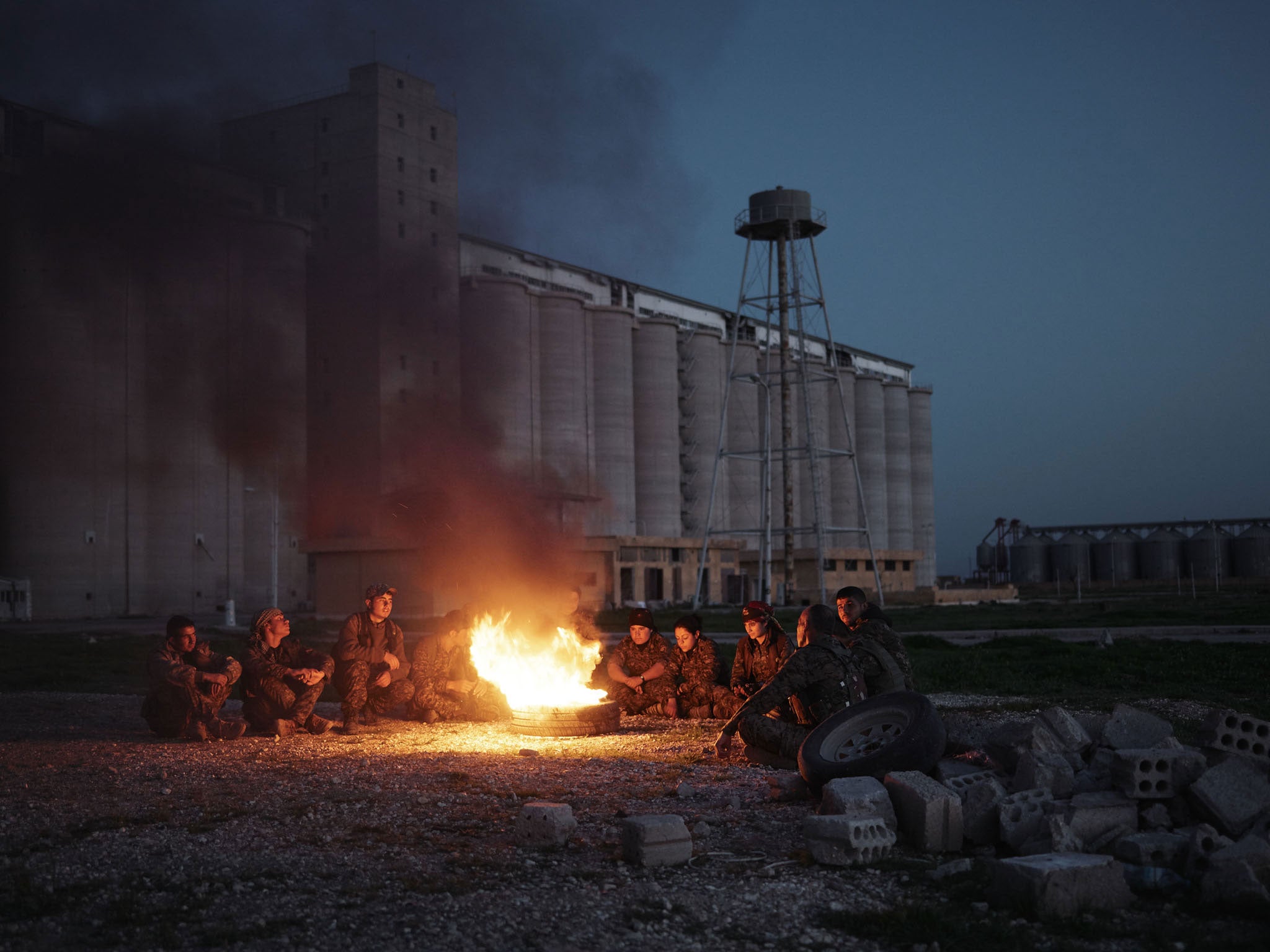 Kurdish fighters gather round a fire after they have liberated Tel Hamis (Joey Lawrence)