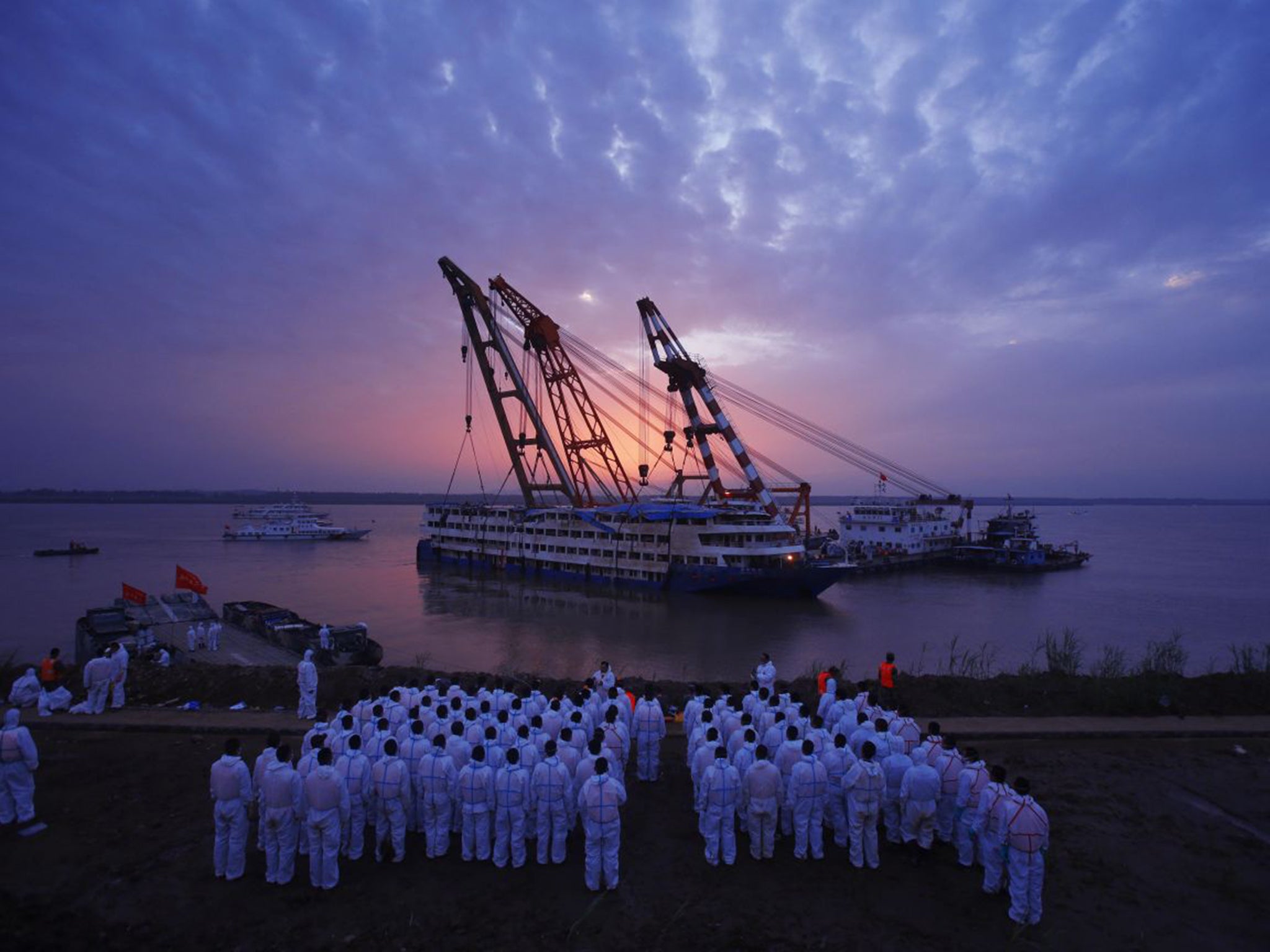 Workers watch as the ship is righted on the Yangtze on Friday