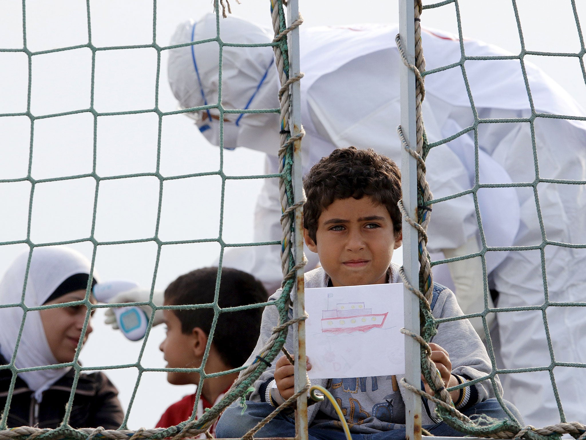 A Syrian child holds a drawing as he waits to disembark from Belgian Navy vessel Godetia in Italy