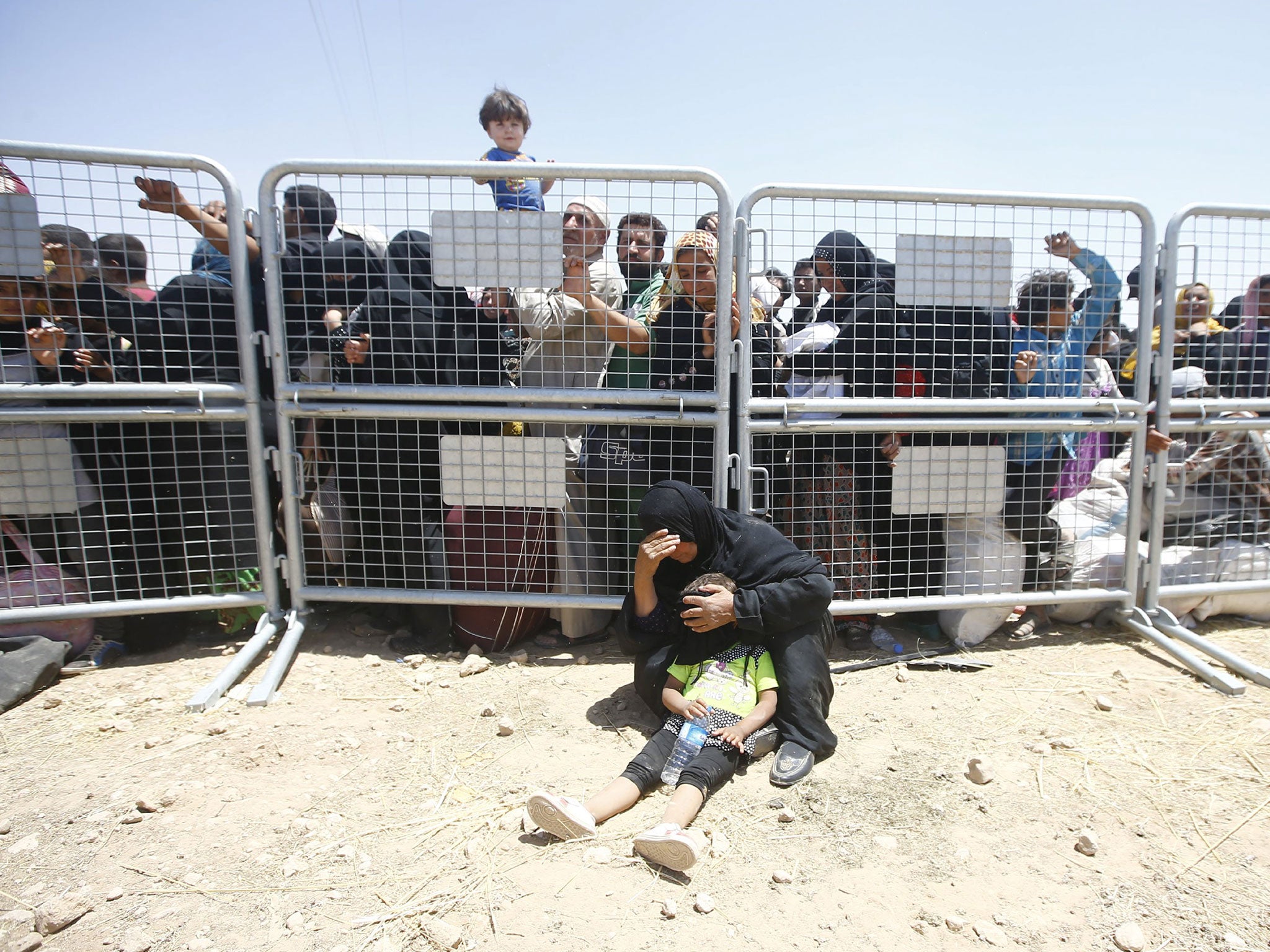 Syrian refugees wait for transportation after crossing into Turkey from the Syrian town of Tal Abyad, near Akcakale in Sanliurfa province, Turkey