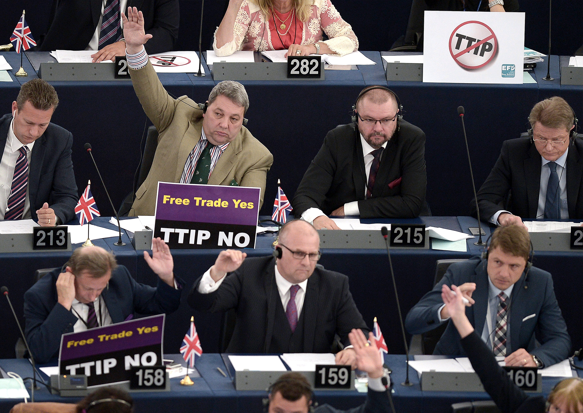 Members of the European Parliament take part in a voting session as they hold signs against TTIP