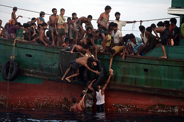 Rohingya migrants pass food supplies dropped by a Thai army helicopter