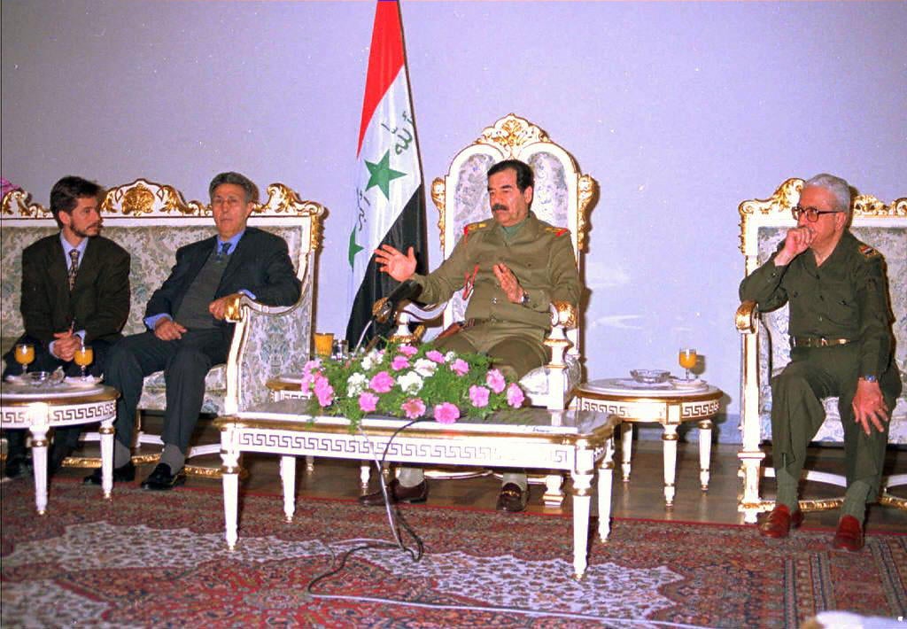 Tariq (right) sits with Saddam Hussein at a meeting in 1997