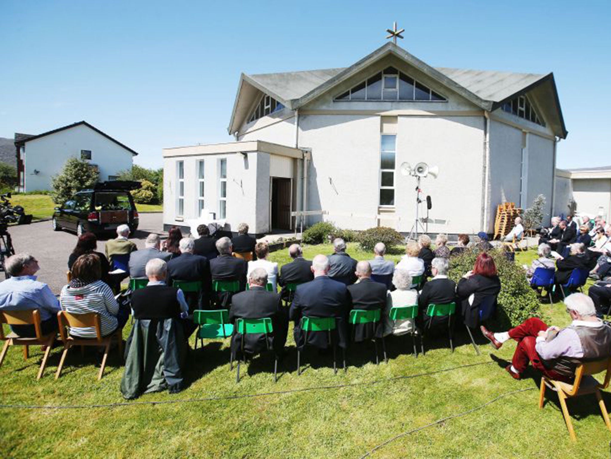 Mourners listen to the funeral Mass for Charles Kennedy outside St John the Evangelist church near Fort William yesterday