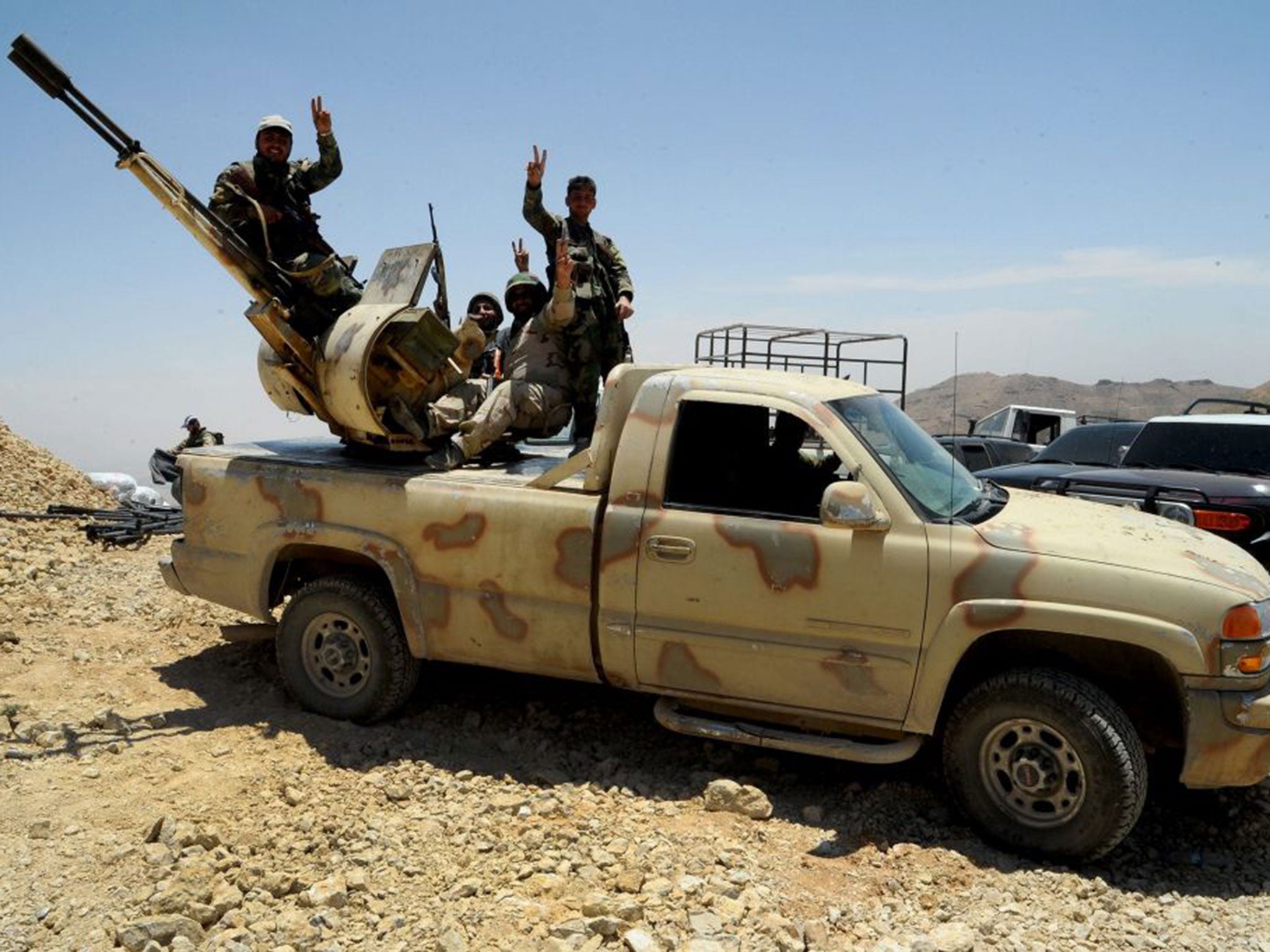 Syrian army soldiers and Hezbollah members flashing the 'Victory' sign in their positions overlooking the Flita height in the Qalamoun mountains