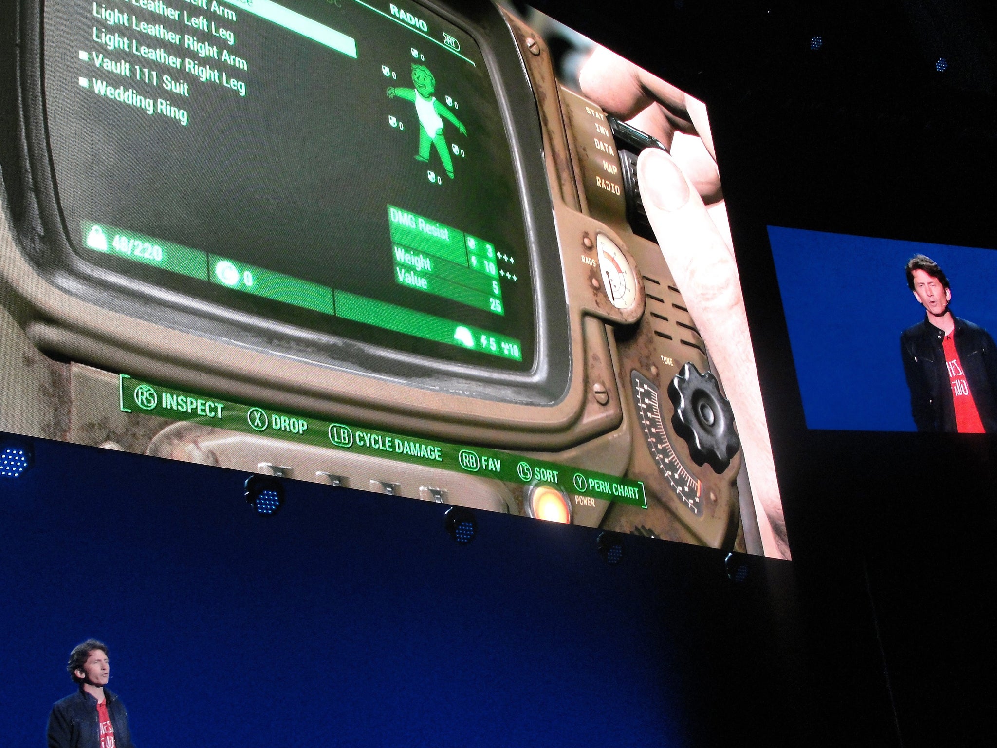 Bethesda Game Studios director Todd Howard (L) is pictured on a large video screen (top R) as he provides a glimpse into a hotly-anticipated 'Fallout 4' video game, a version of which will include a real-world version of in-game Pip-Boy wrist wear