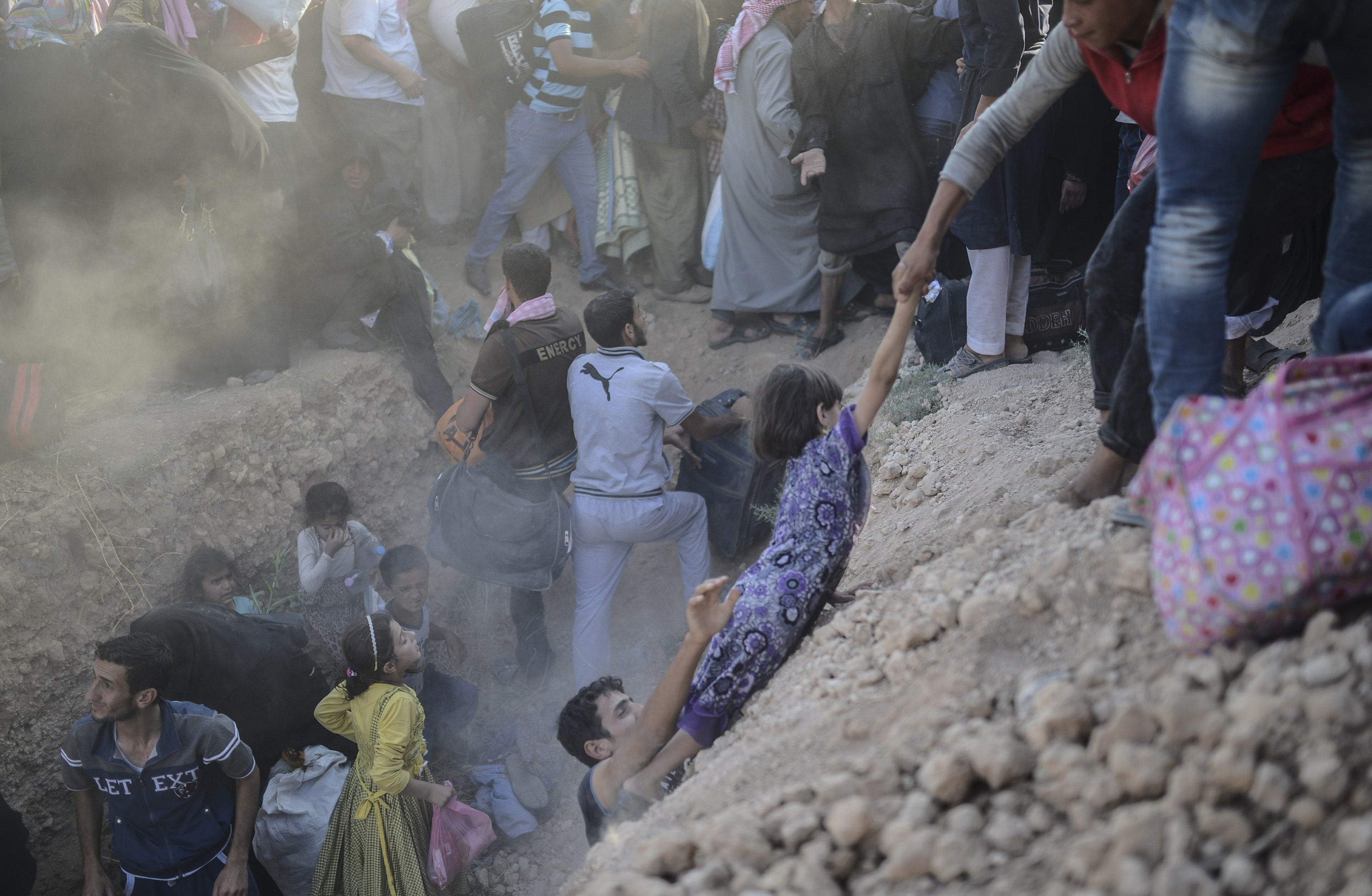 A family flee amid the scrum through broken fences (Photo: BULENT KILIC/AFP/Getty Images)