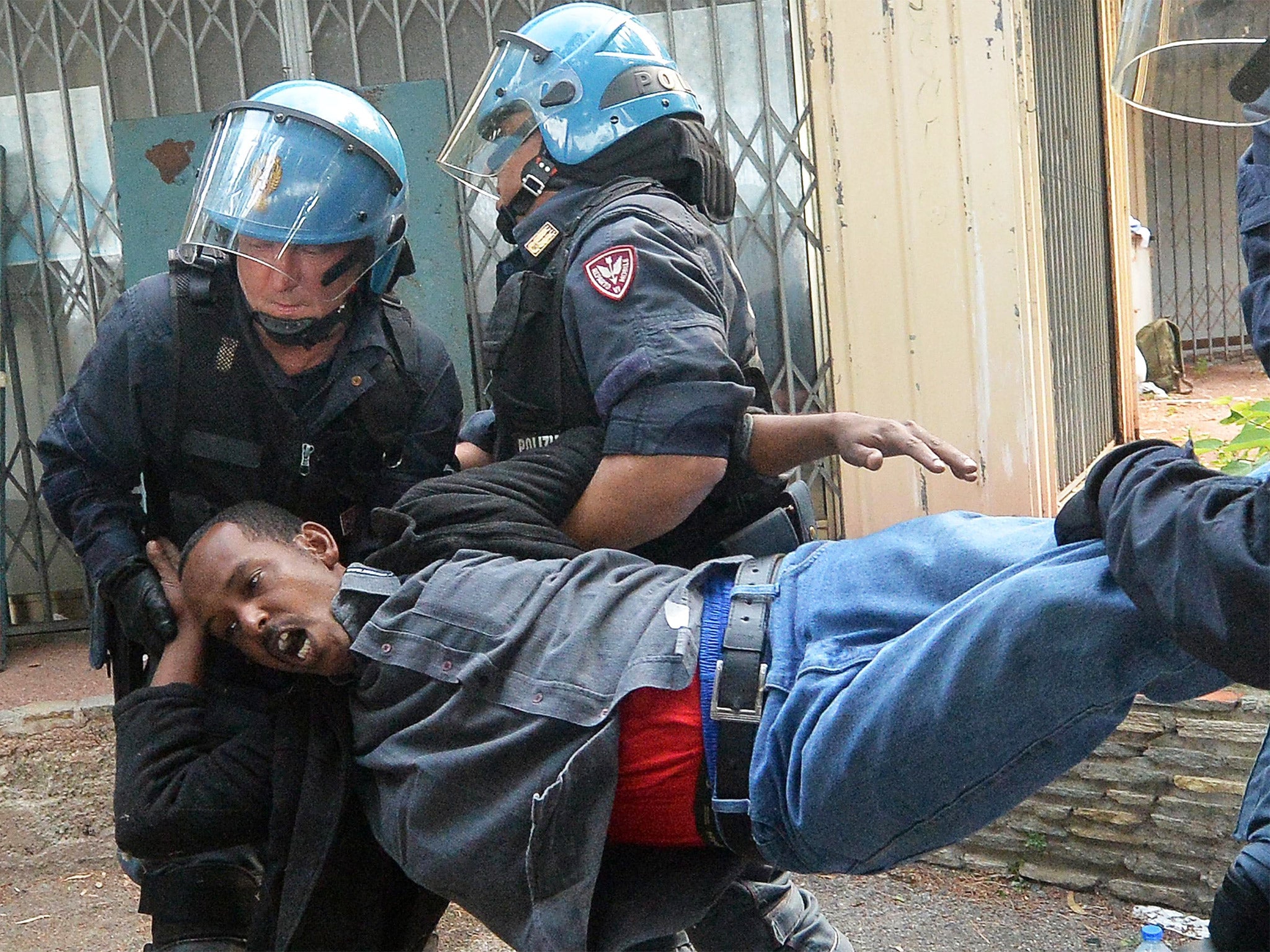 A migrant is carried by Italian police in Ventimiglia, Italy. Police reportedly removed migrants from under a railway bridge