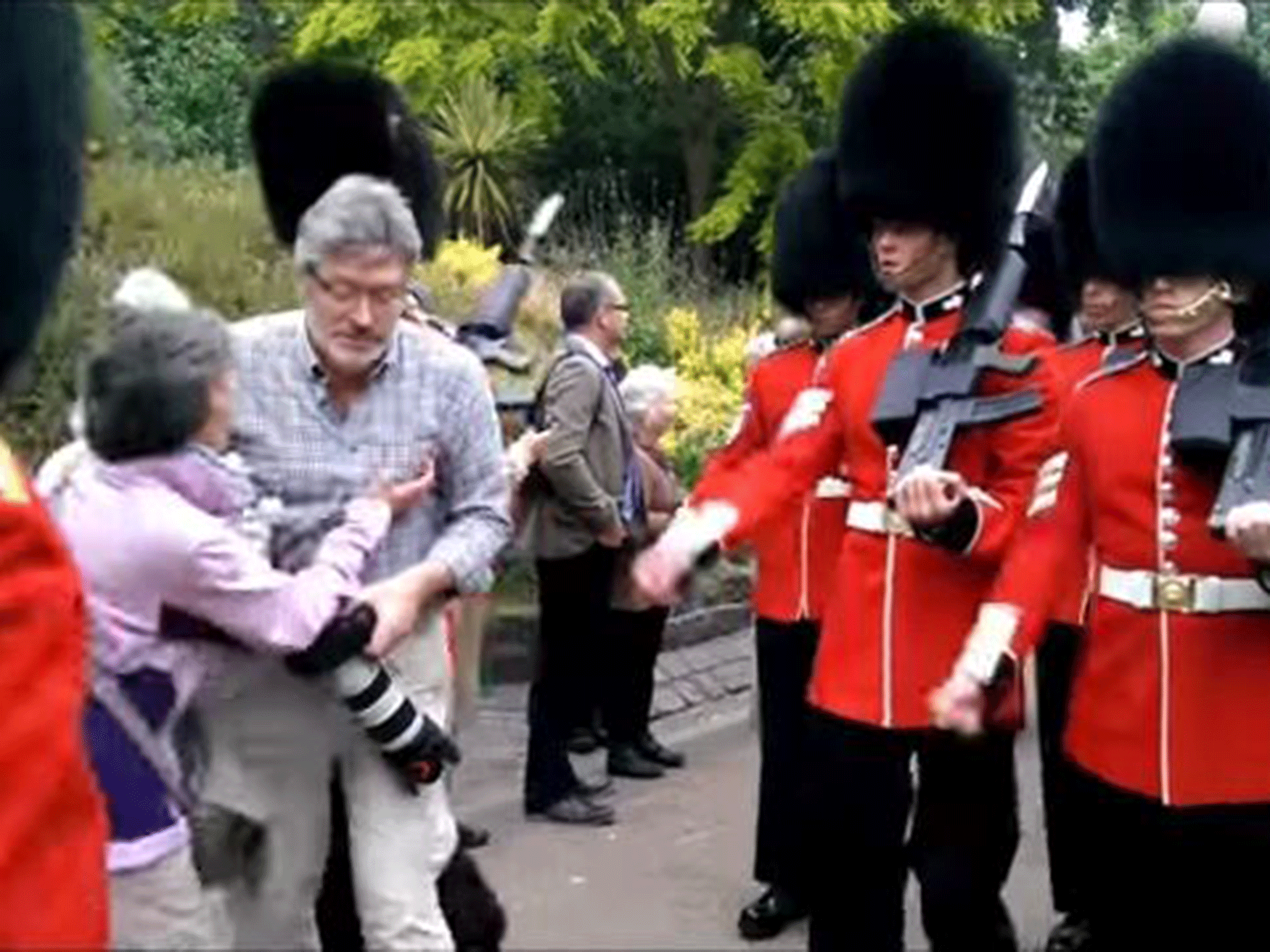 Footage has emerged of the moment a man with a camera is barged into by the Queen's Guards as he stands in their way