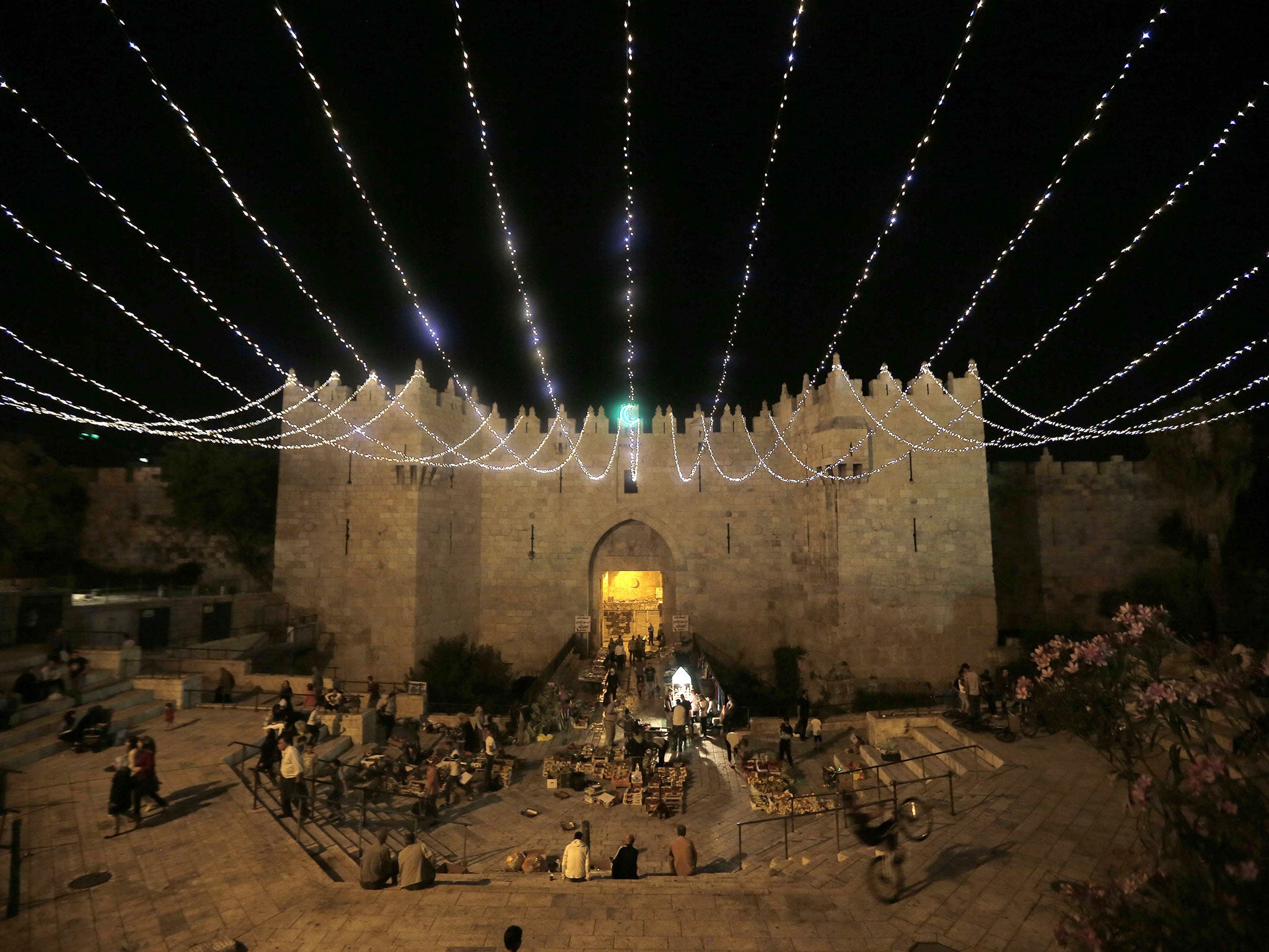 People walk under lights decorating Damascus Gate outside the old city of Jerusalem, as Muslims around the world prepare for the announcement of the fasting month of Ramadan