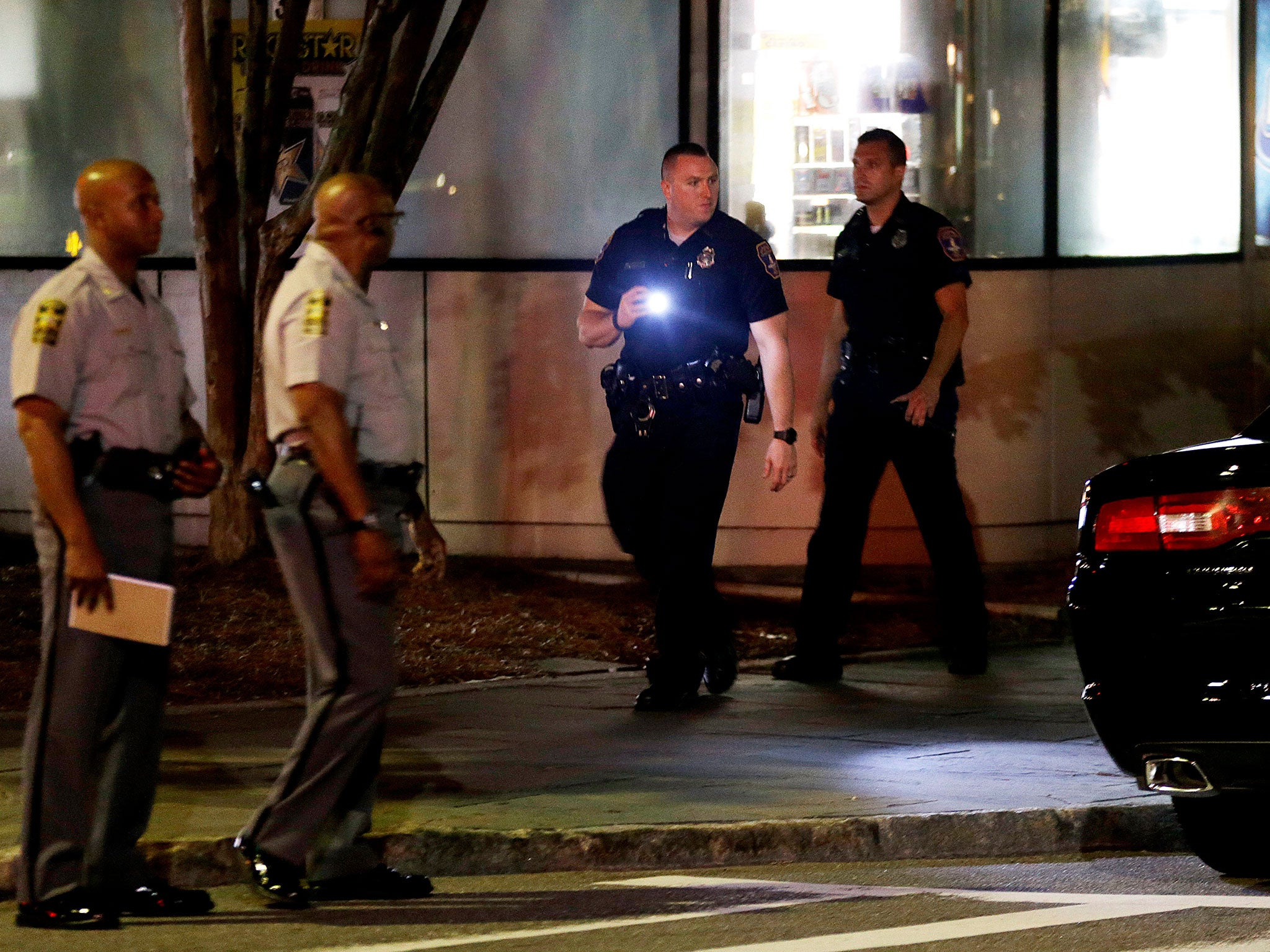 A police officer uses a flashlight while searching the area following a shooting in Charleston