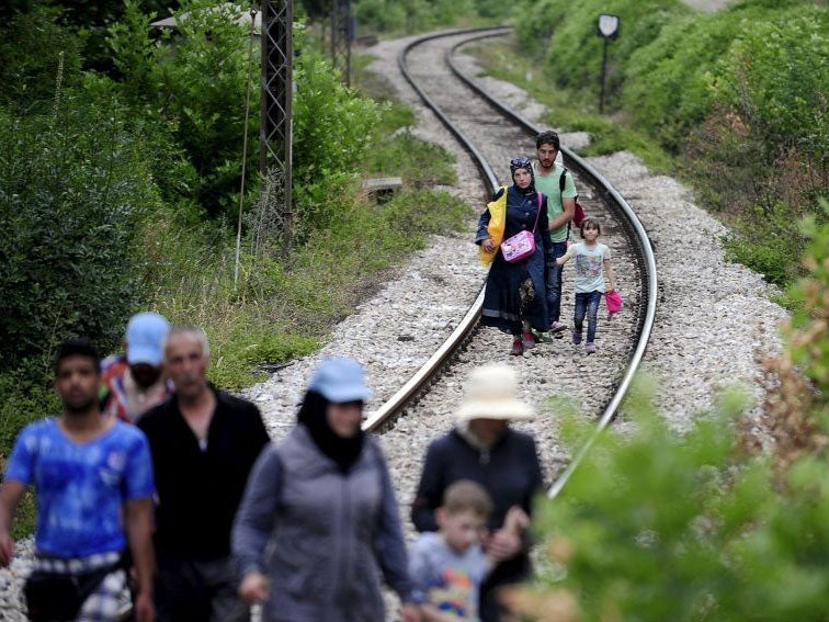 Syrian refugees walking on train tracks through Macedonia on the Western Balkans migration route, after entering Europe through Greece