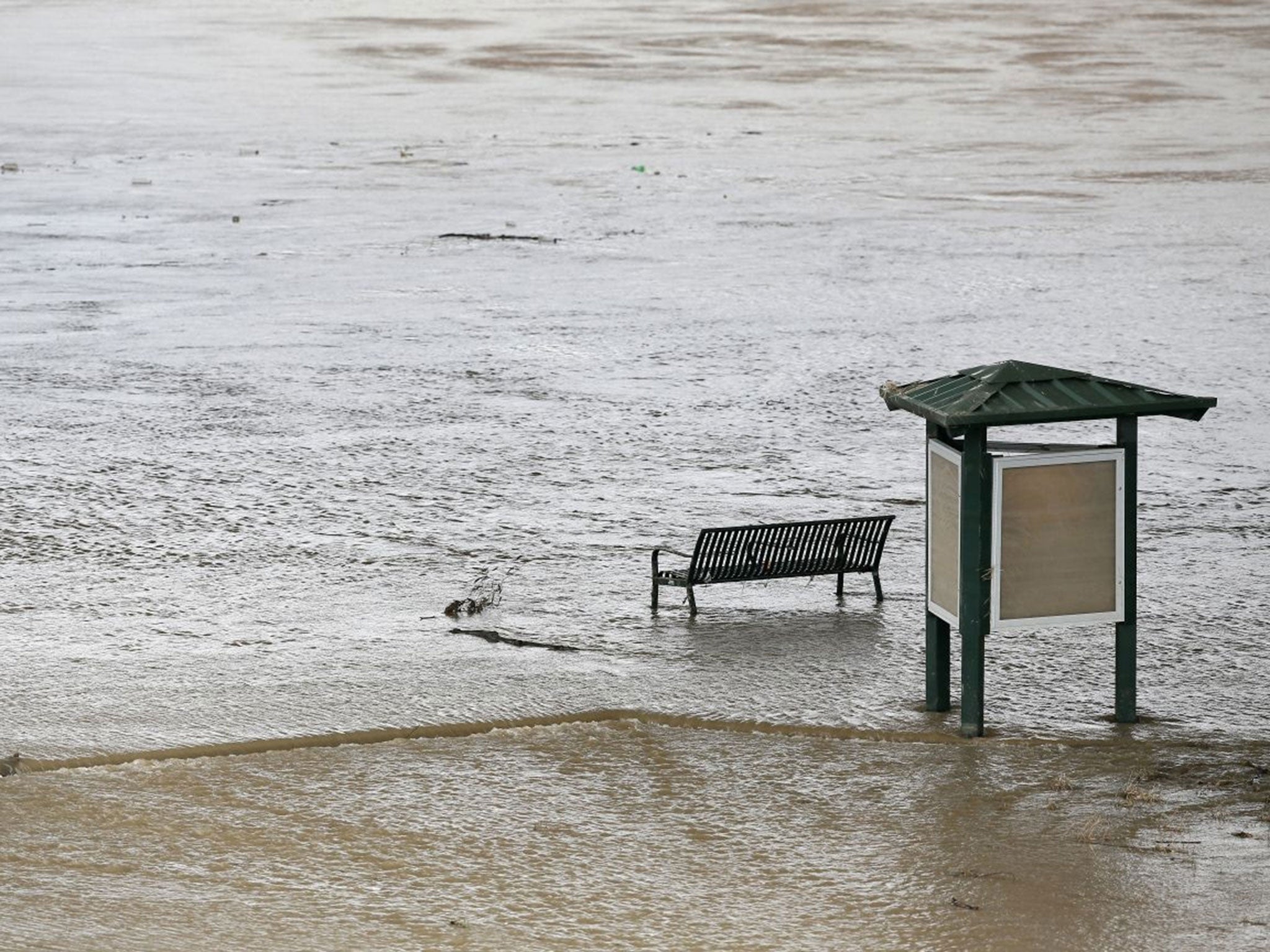 Water flows under a partially submerged park bench along a trail by Skyline Bridge Park on the Trinity river, Dallas. (AP/Tony Gutierrez)