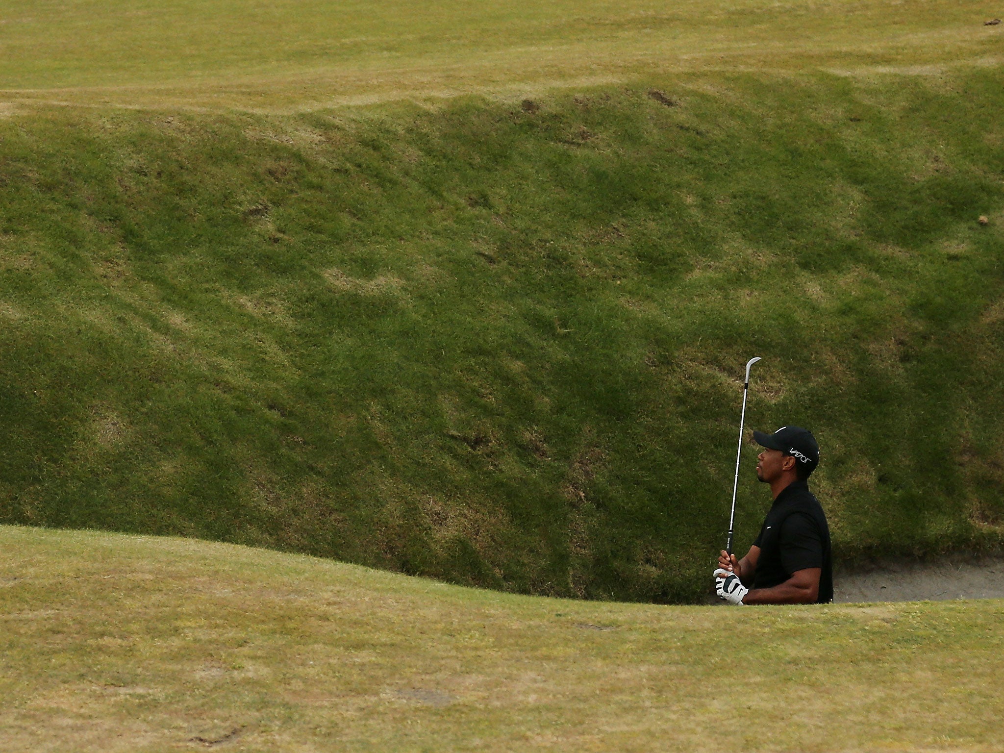 Tiger Woods chips out of a deep bunker