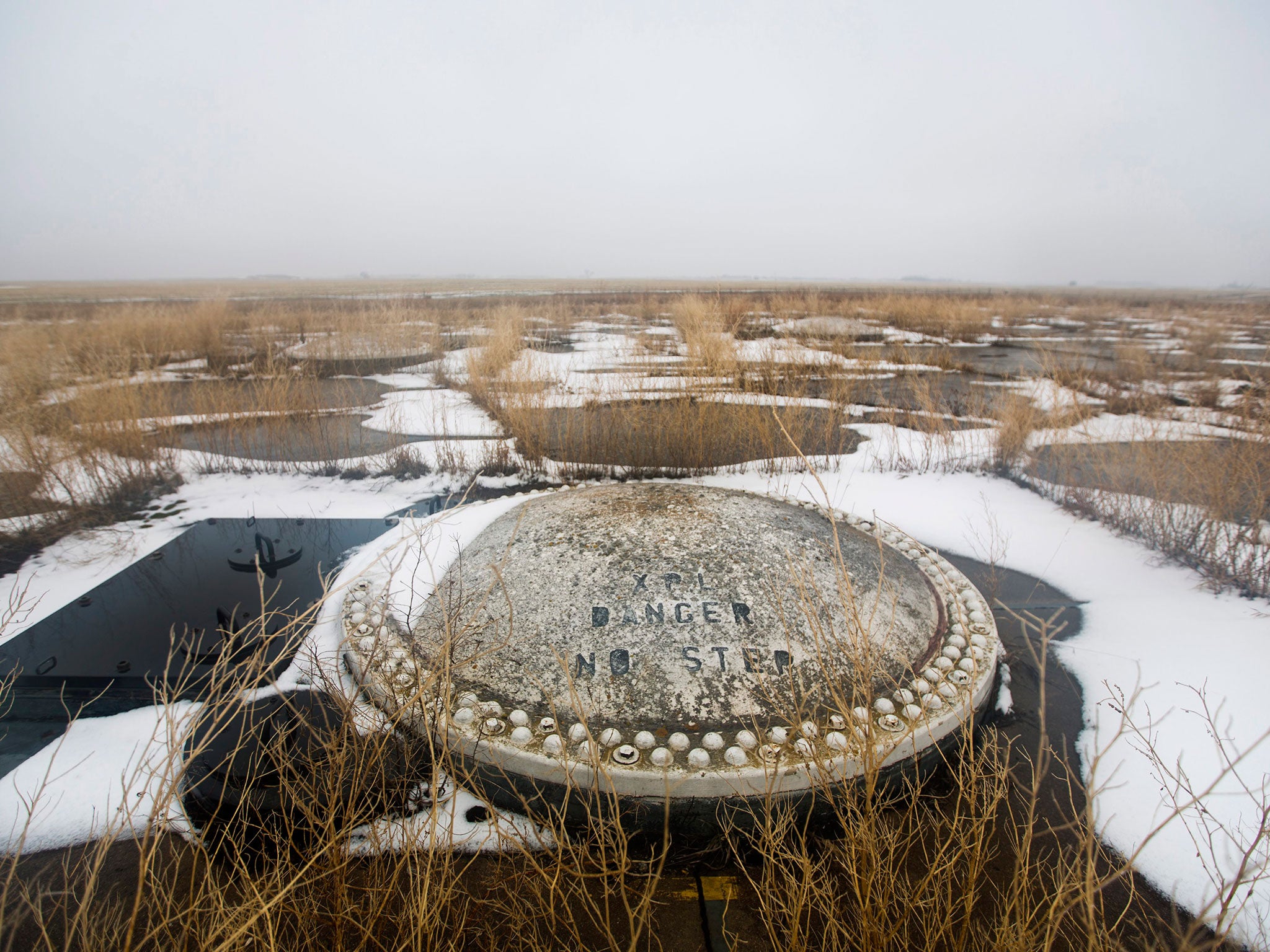 Weeds poke through the concrete surrounding the cell cover of a missile silo that once contained a Sprint thermonuclear missile near Hampden, North Dakota