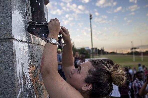 A student helps 'free' a protester in chains on top of where the Cecil Rhodes statue stood moments before it was removed at the University of Cape Town in April 2015