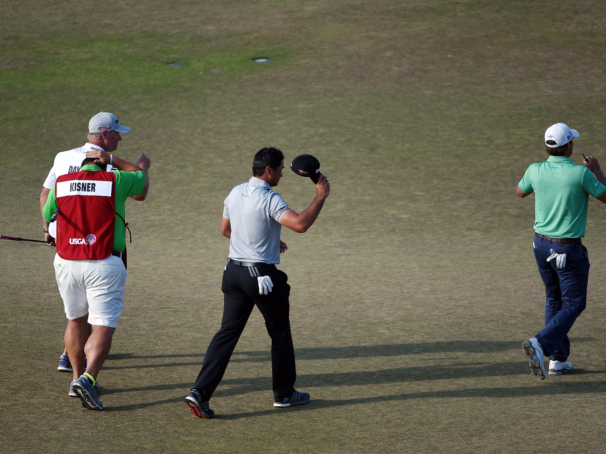 Jason Day of Australia waves as he walks off the 18th green alongside Kevin Kisner