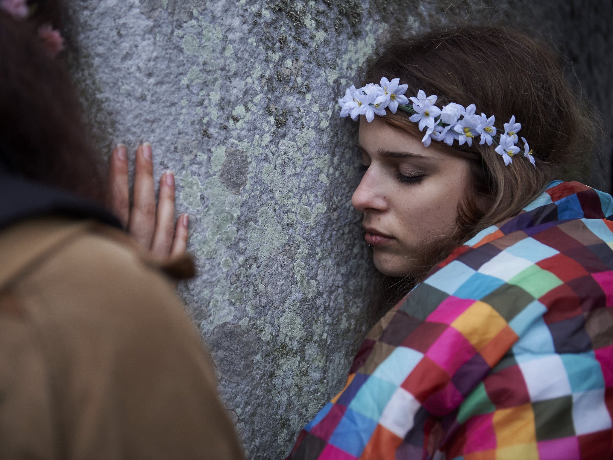 A reveller rests her head on a megalith as she and others celebrate the pagan festival of Summer Solstice this morning