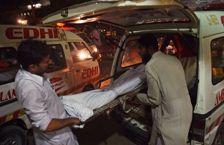 Relatives shift the dead body of a heatwave victim into an ambulance at the EDHI morgue in Karachi on June 21, 2015