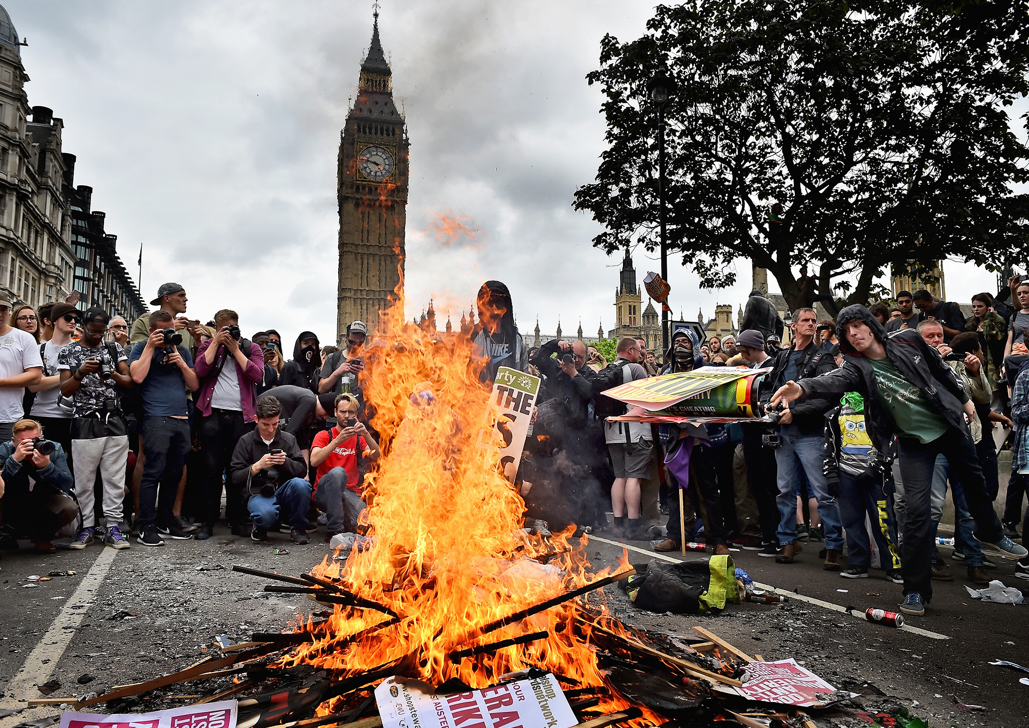 Protestors set fire to placards in central London during demonstrating against austerity and spending cuts on June 20, 2015 in London