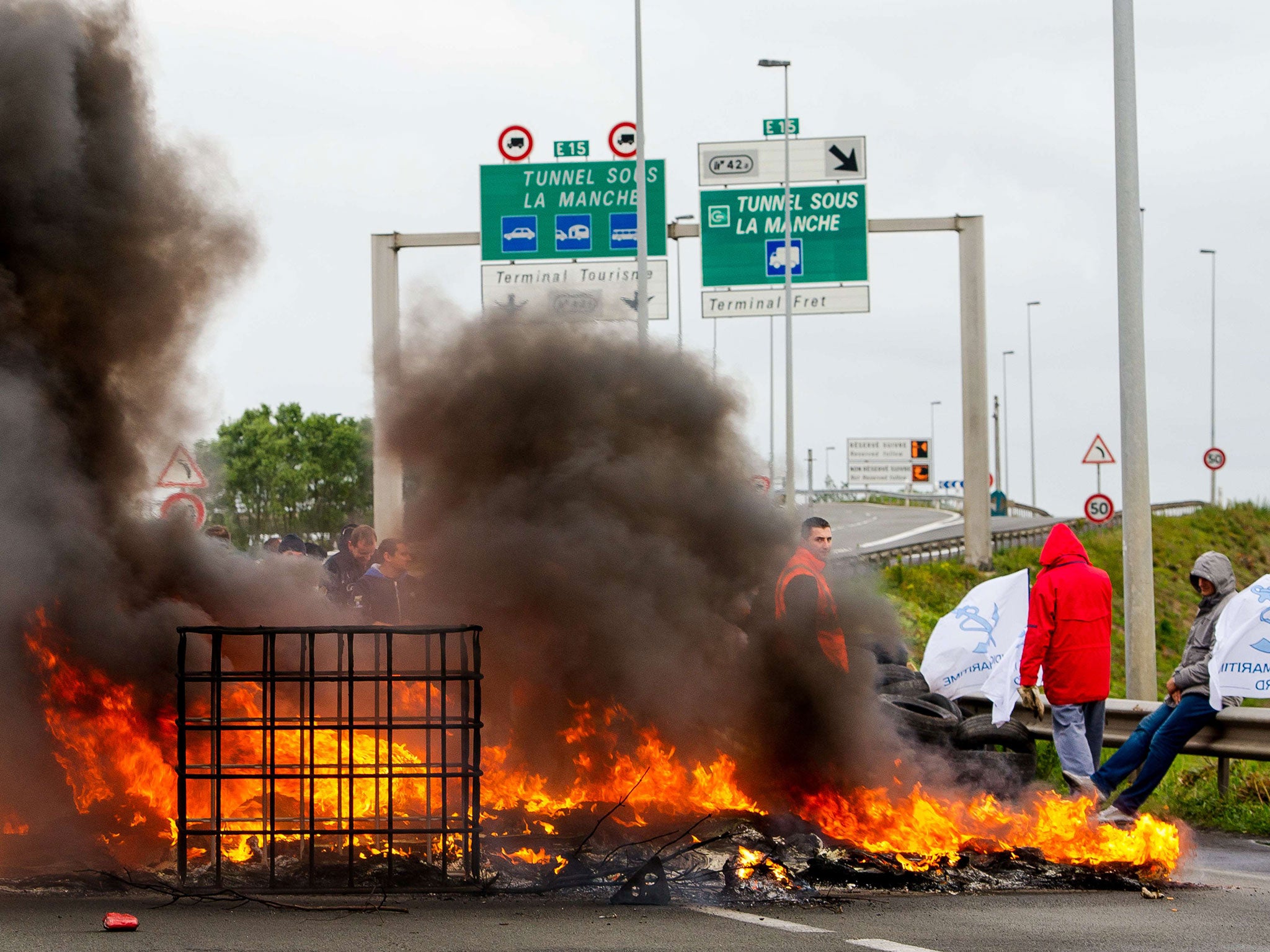 Striking employees of the French company MyFerryLink, a cross-channel ferry service, stand in front of tyres set on fire as they block the access to the Channel Tunnel in Calais (Getty)