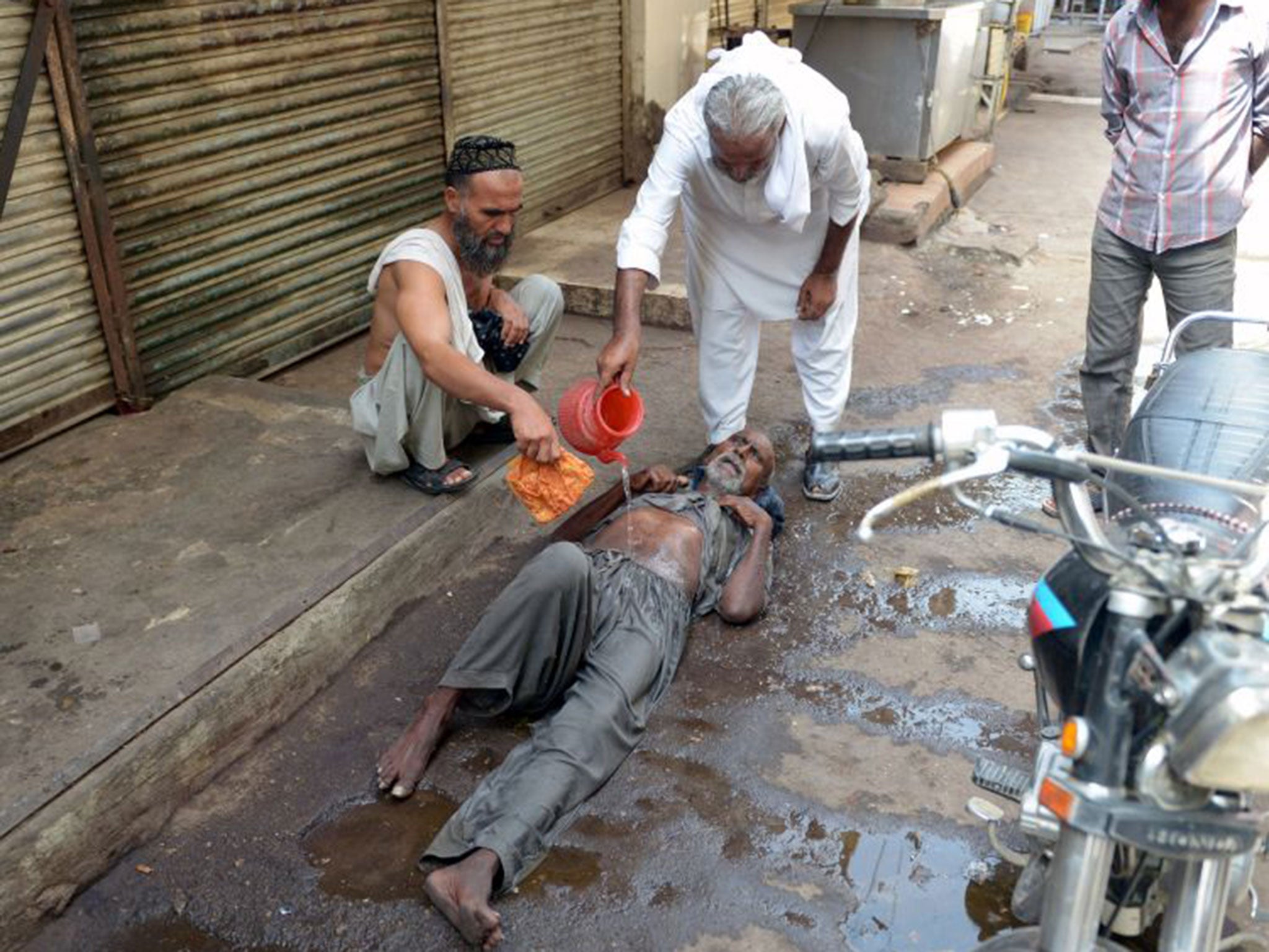 A Pakistani resident helps a heatstroke victim at a market area during a heatwave in Karachi.