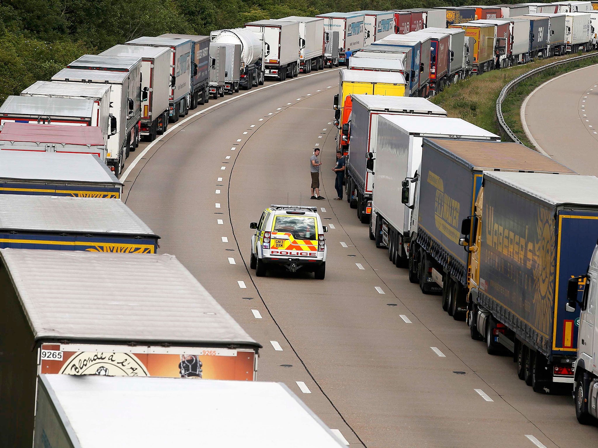 A police vehicle drives past lorries are backed up on the M20 motorway which leads from London to the Channel Tunnel terminal at Ashford and the Ferry Terminal at Dover