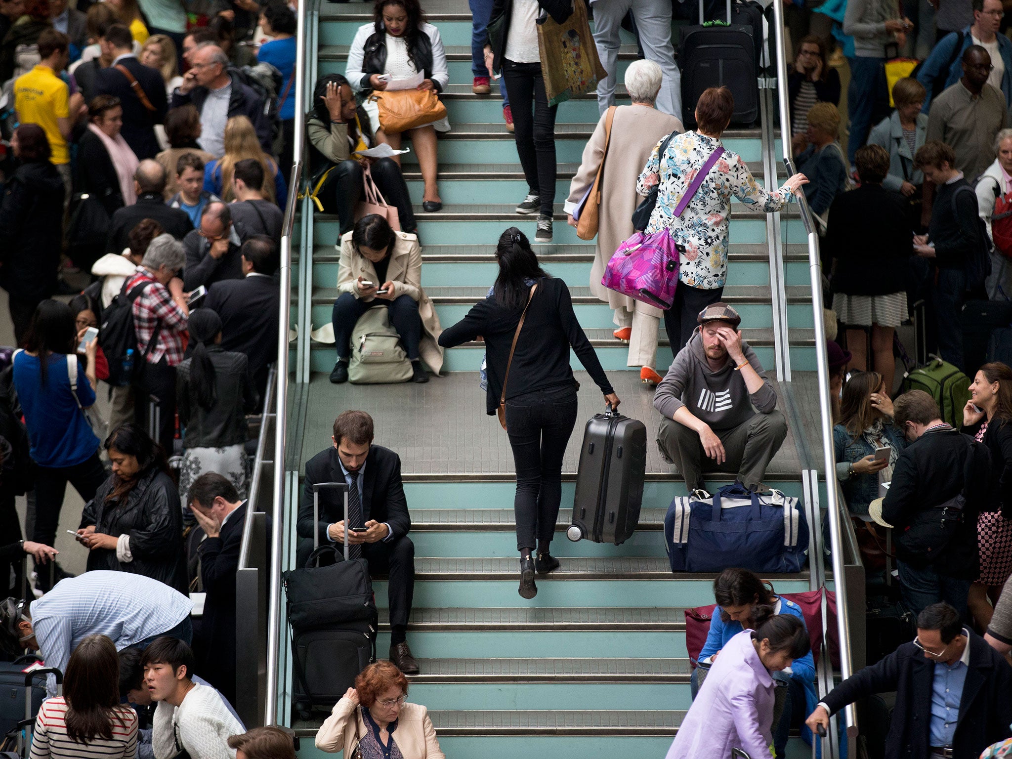 Passengers sit on stairs after being stranded by cancelled Eurostar trains at St. Pancras station in London