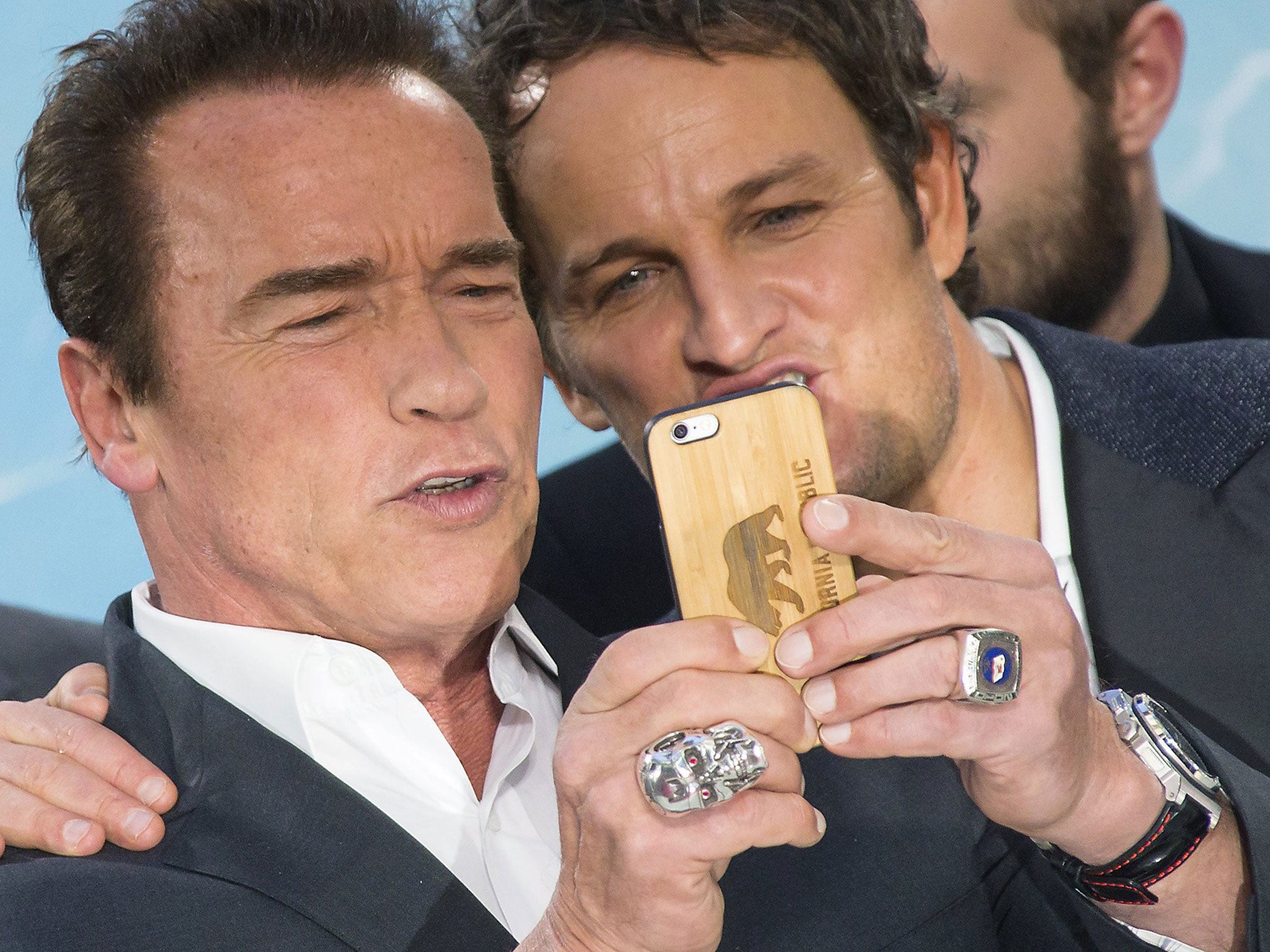 Arnold Schwarzenegger and Jason Clarke take a selfie as they arrive at the red carpet for the premiere of the film "Terminator Genisys" in Berlin, Germany