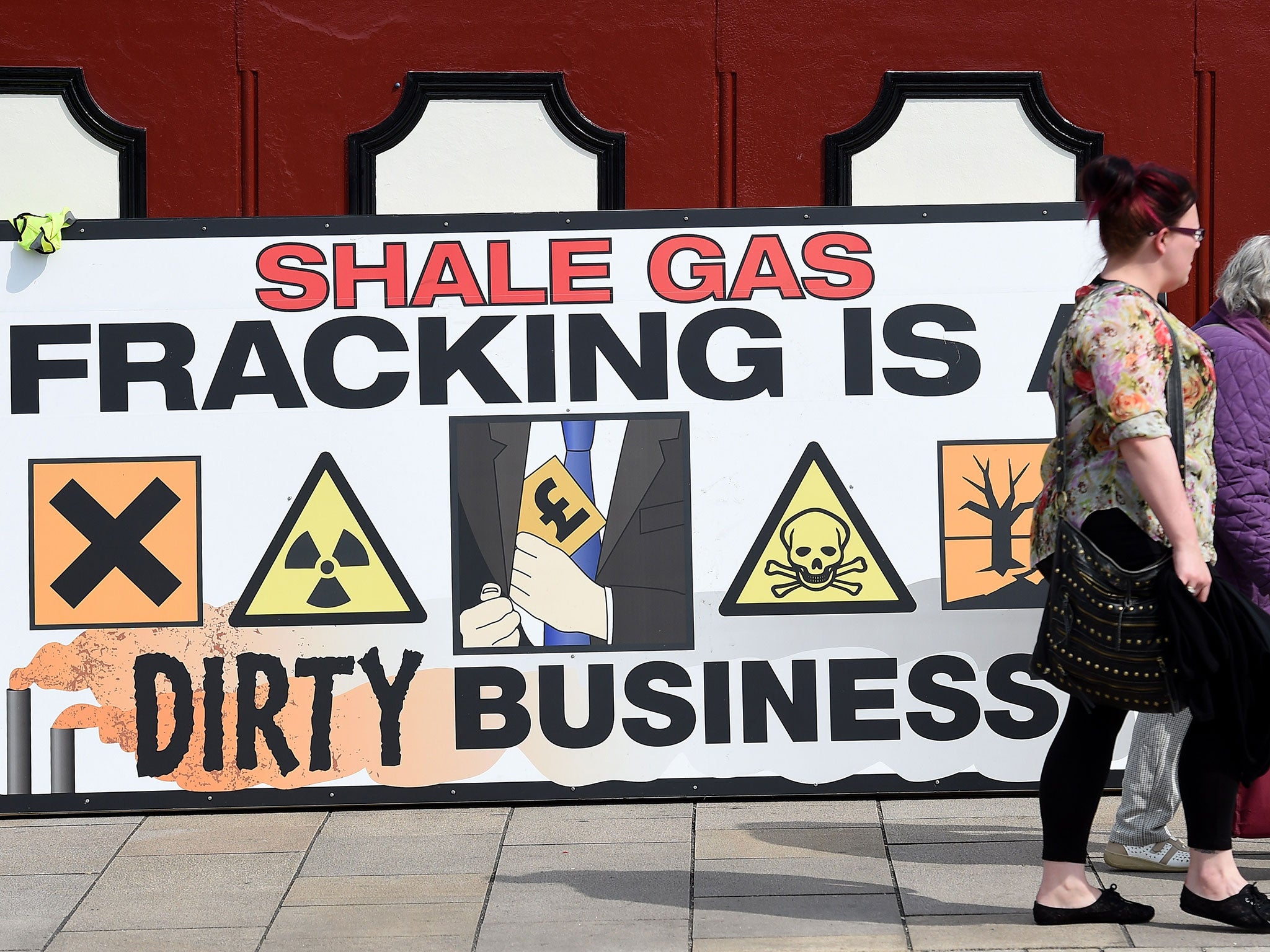 People walk past an anti-fracking banner as demonstrators outside Lancashire County Hall in Preston, protest against the applications from energy firm Cuadrilla to start two fracking operations on nearby sites