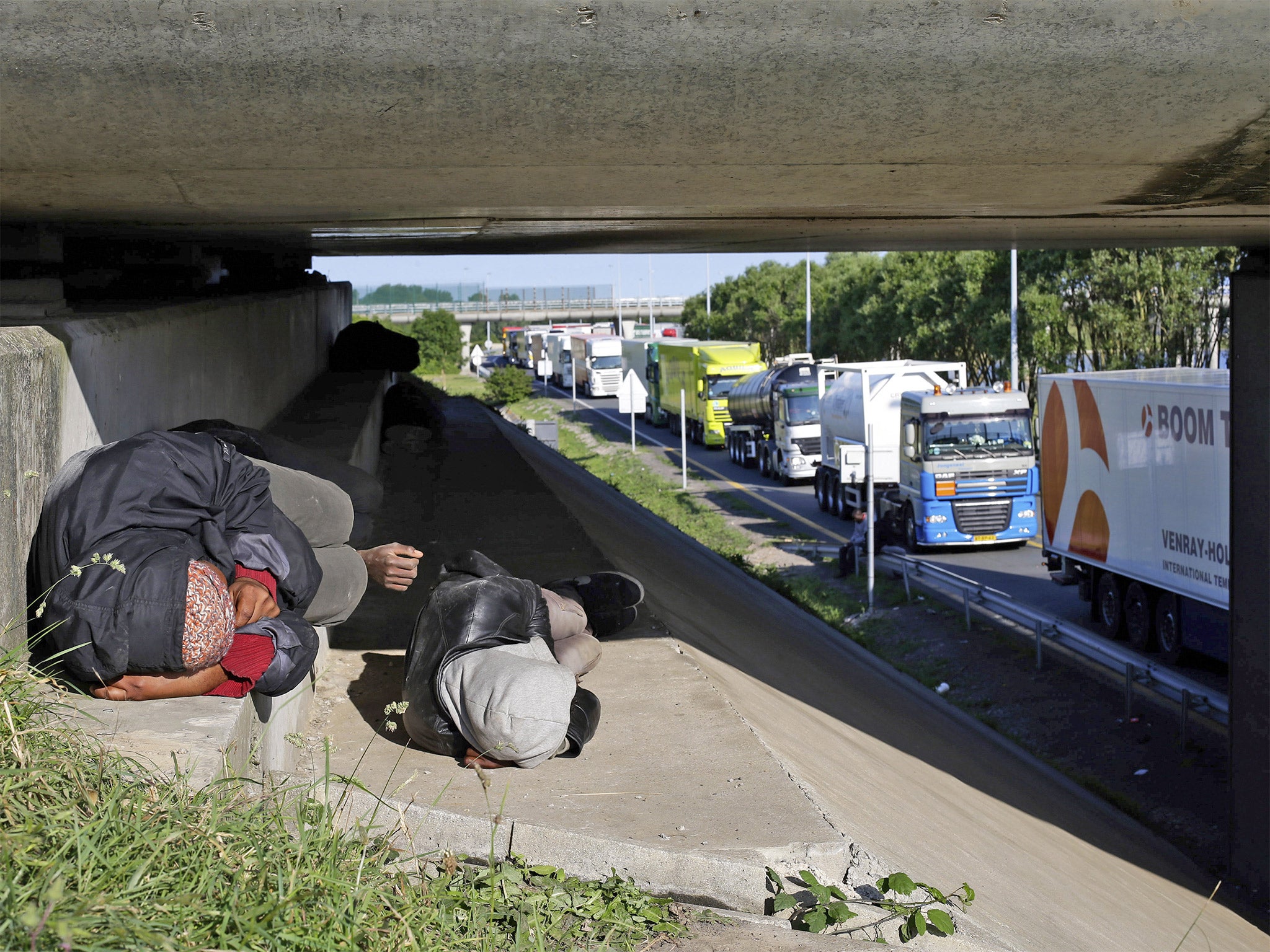 Migrants sleep along a motorway leading to the ferry port in Calais