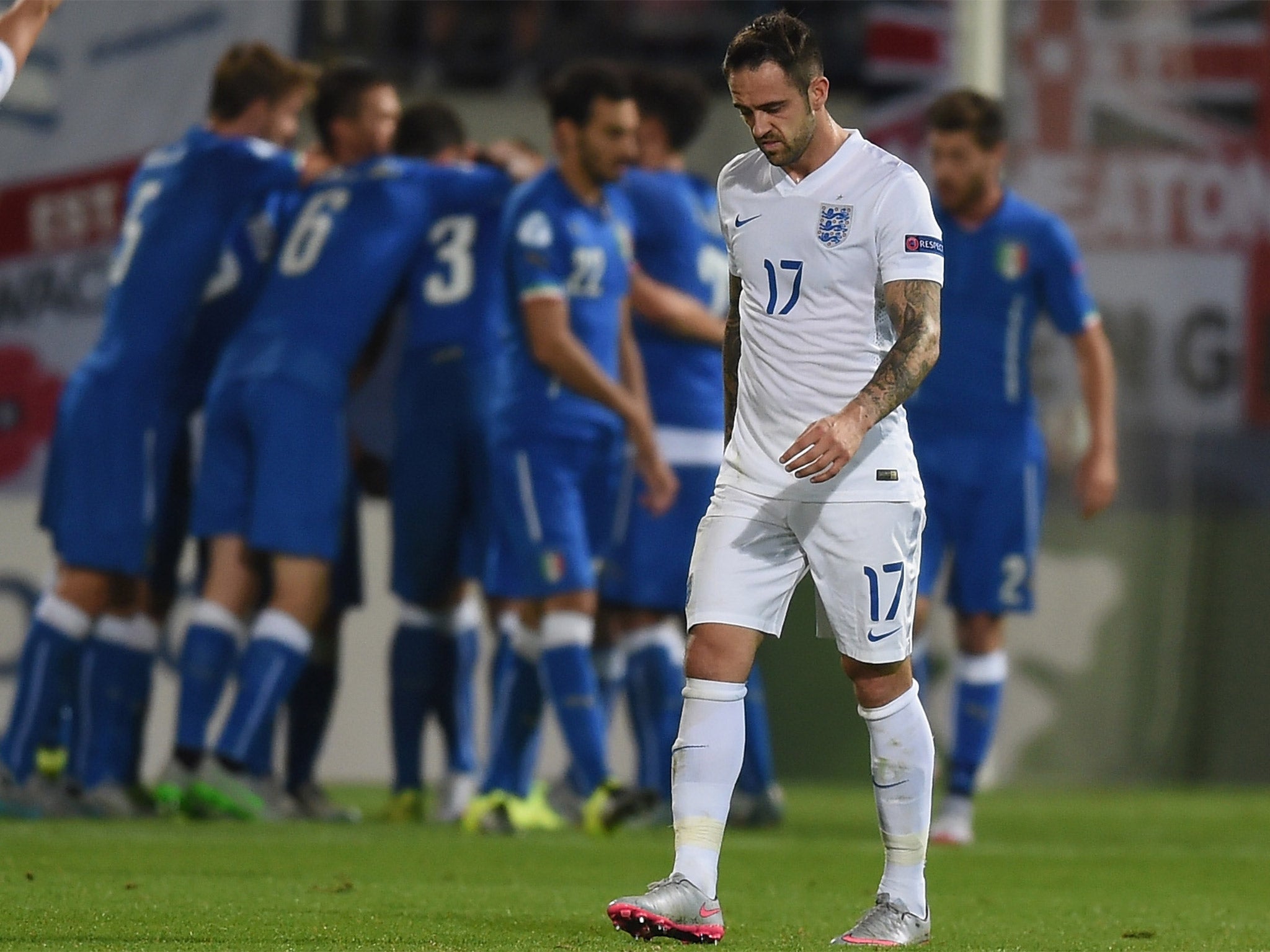 Danny Ings looks dejected as the Italians celebrate their third goal