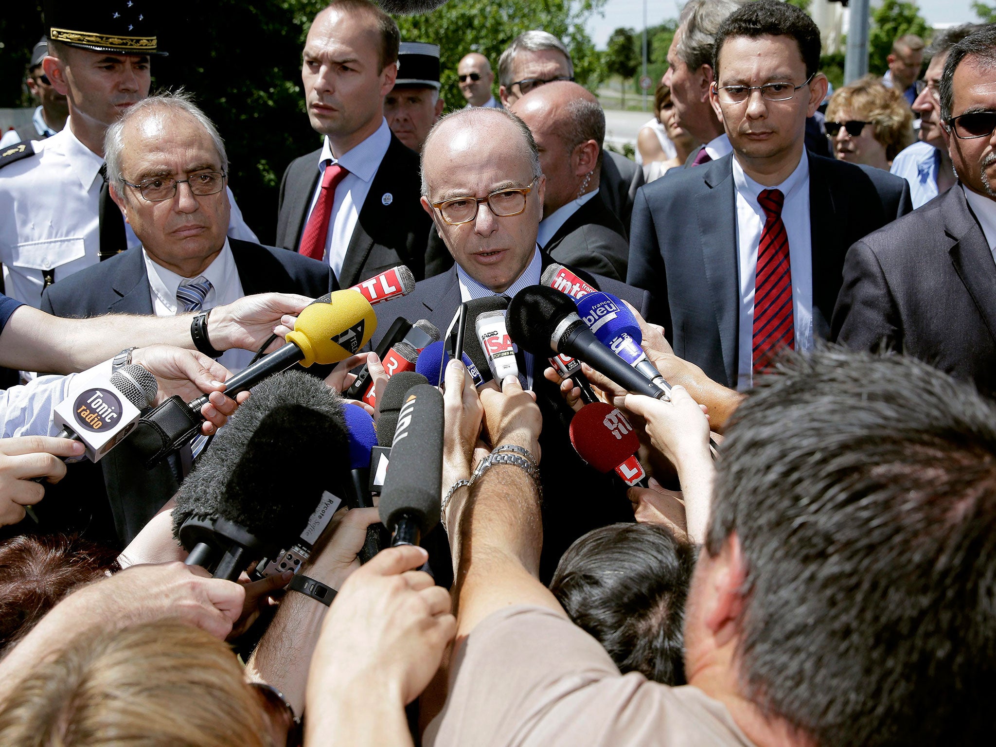 French Minister of Interior Bernard Cazeneuve (C) talks to media after he arrived at the scene of a suspected Islamist attack, outside a factory in Saint-Quentin-Fallavier