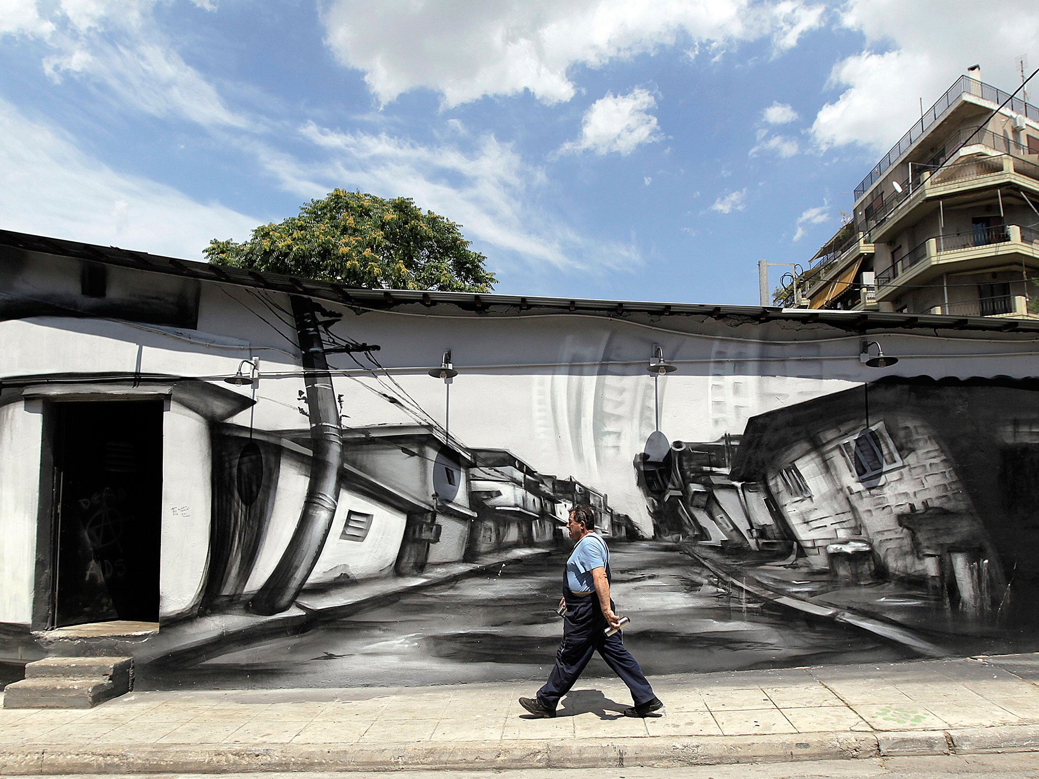 A worker walks in the empty industrial zone of central Athens, 26 June 2015