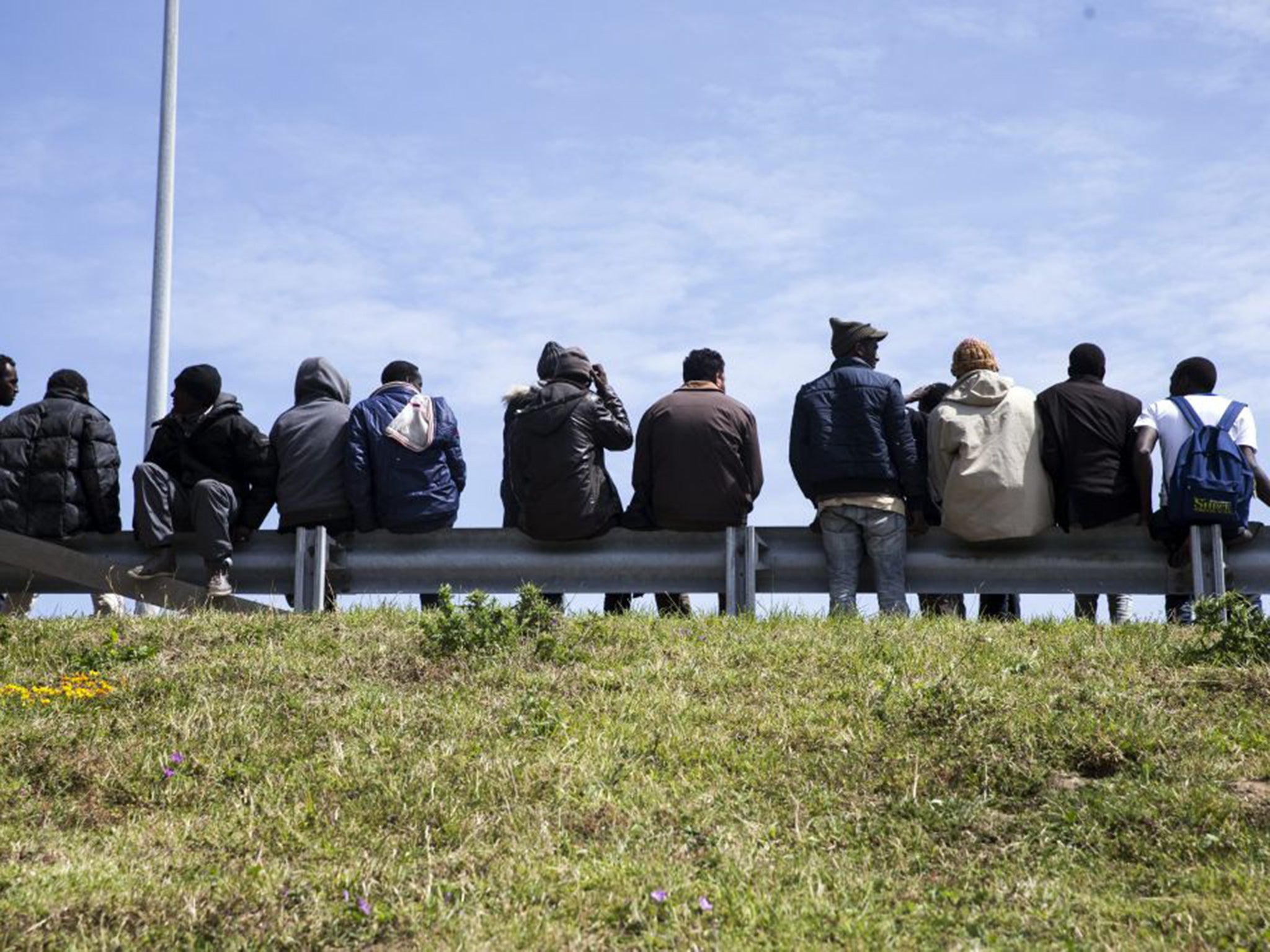 Tense wait: Migrants by the Calais access road to the Channel Tunnel seek a vehicle that they can hide in and which will take them across to Britain